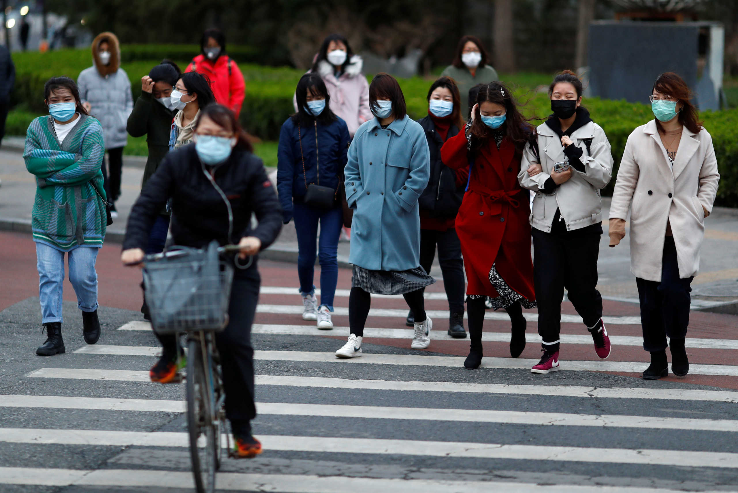 People wearing masks cross a street during after work rush hour, as businesses start returning to their normal routine following the new coronavirus disease (COVID-19) outbreak, in Beijing, China, March 26, 2020. REUTERS