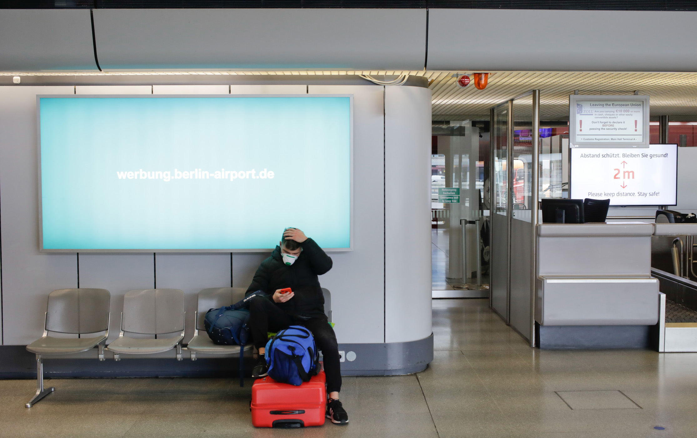 A traveller sits at a check-in counter at the Tegel airport, as the spread of coronavirus disease (COVID-19) continues in Berlin, Germany, March 30, 2020. REUTERS