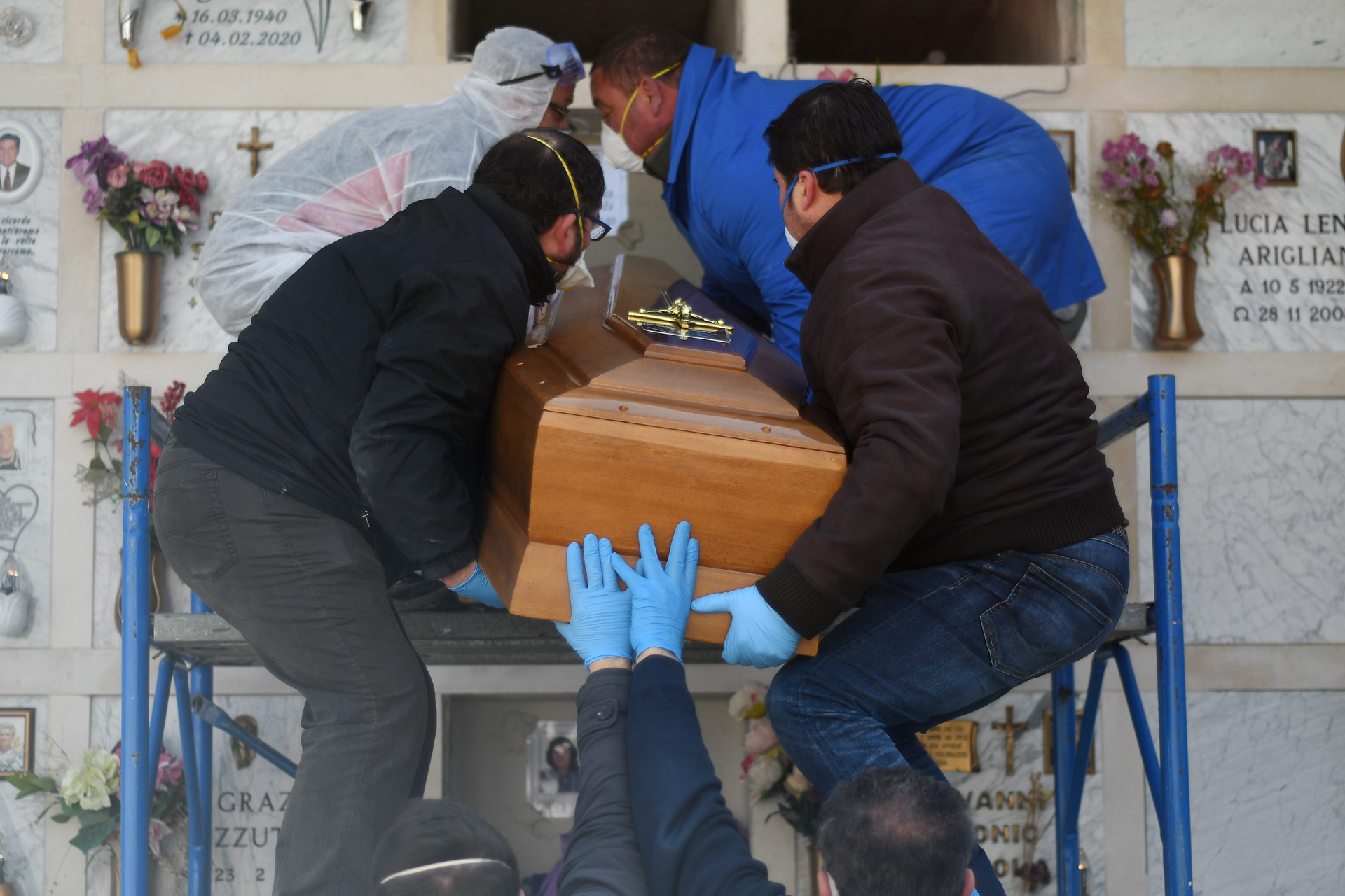Funeral service workers bury a coffin of a victim of coronavirus disease (COVID-19) during a ceremony in the southern town of Cisternino, Italy March 30, 2020. REUTERS