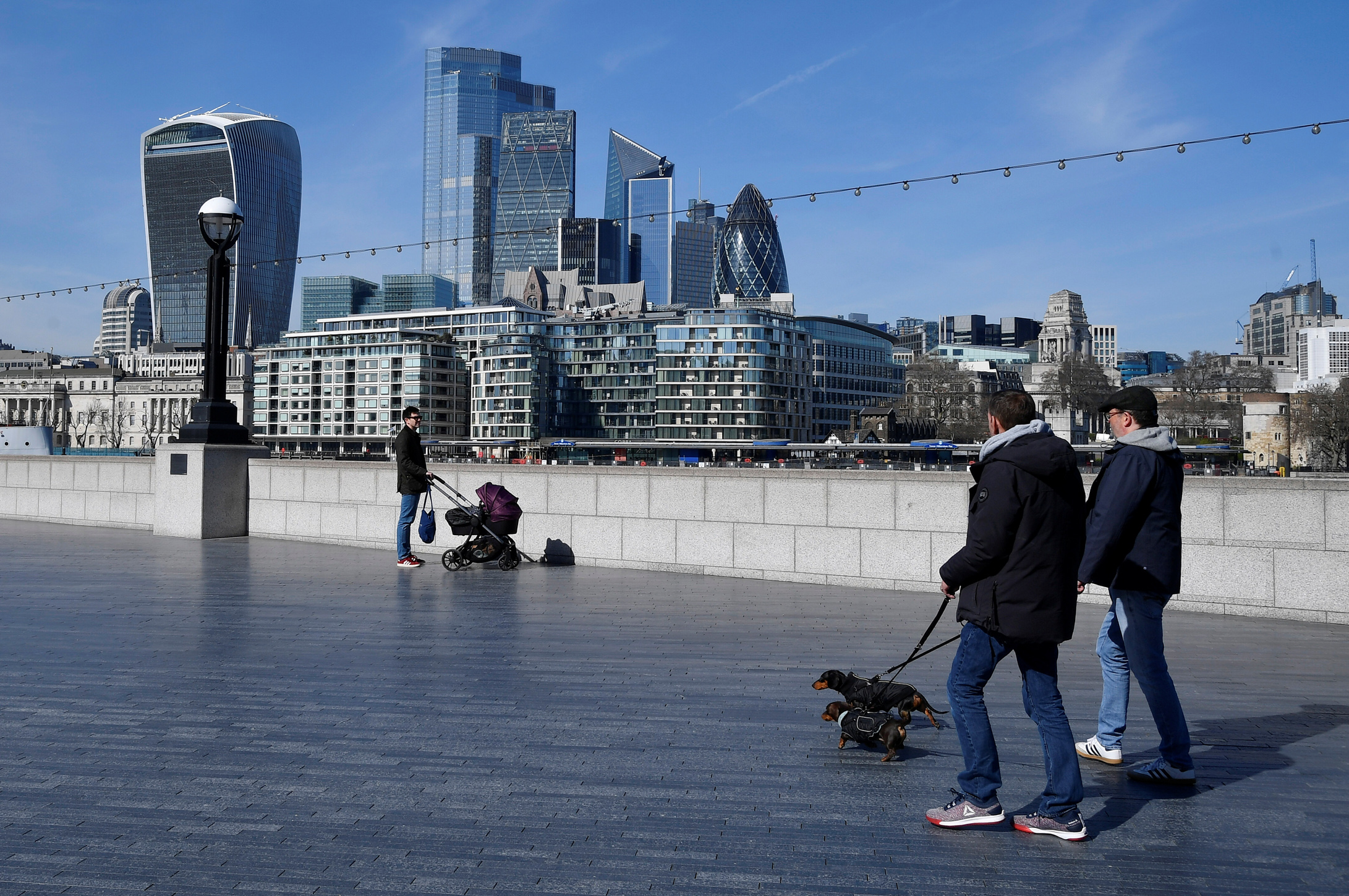 People walk their dogs as the spread of the coronavirus disease (COVID-19) continues, in London, Britain, March 23, 2020. REUTERS
