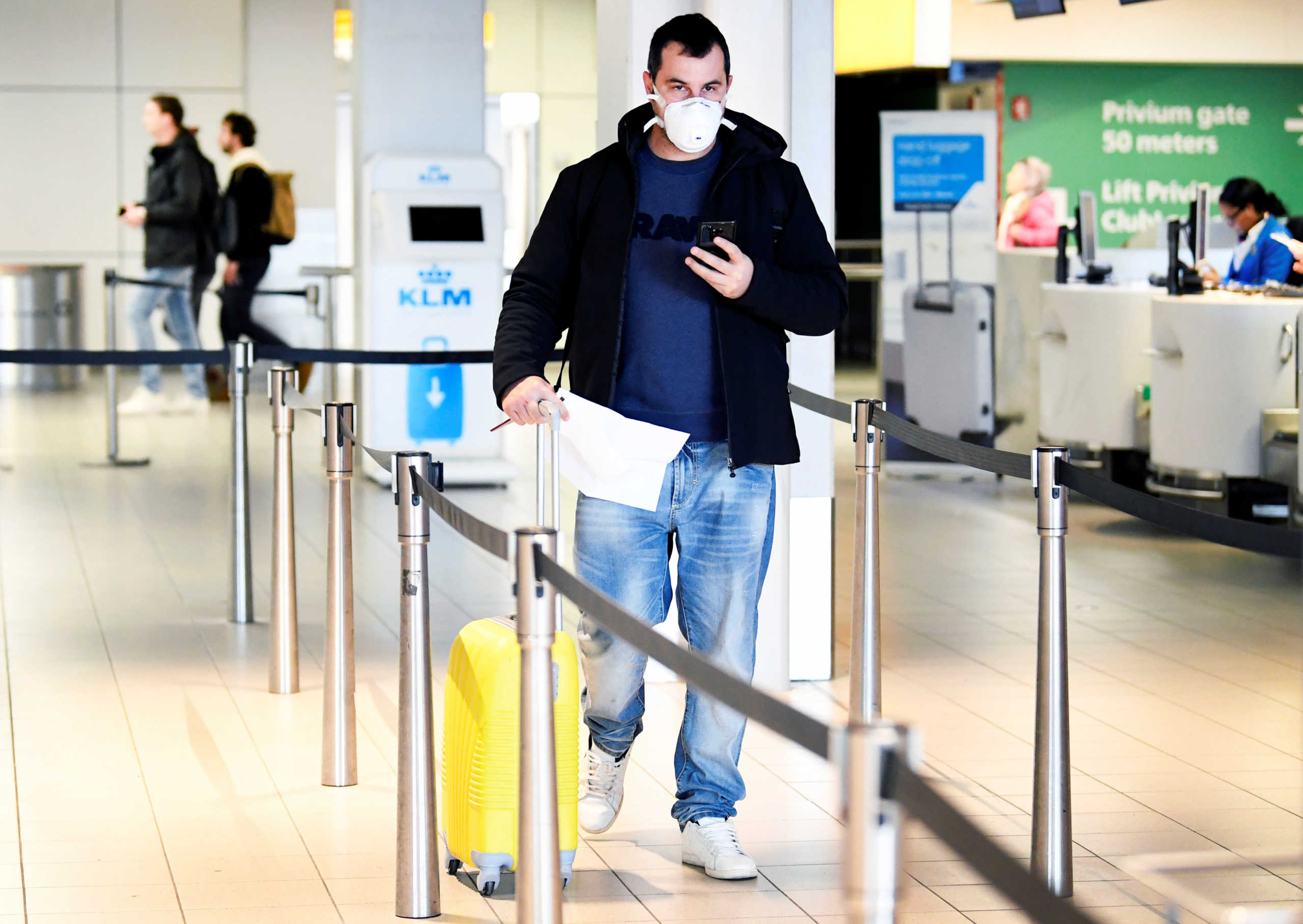 A traveler wears a mask in the departure hall at the KLM Service Desk, as the travel ban for European countries announced by U.S. President Donald Trump has major consequences for the world of travel and travelers that have just arrived from U.S., in Schiphol, Netherlands March 12, 2020. REUTERS