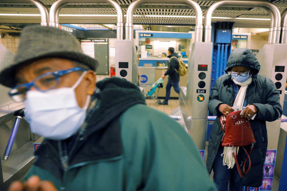 Commuters wearing masks enter the subway system in New York, U.S., March 12, 2020. REUTERS