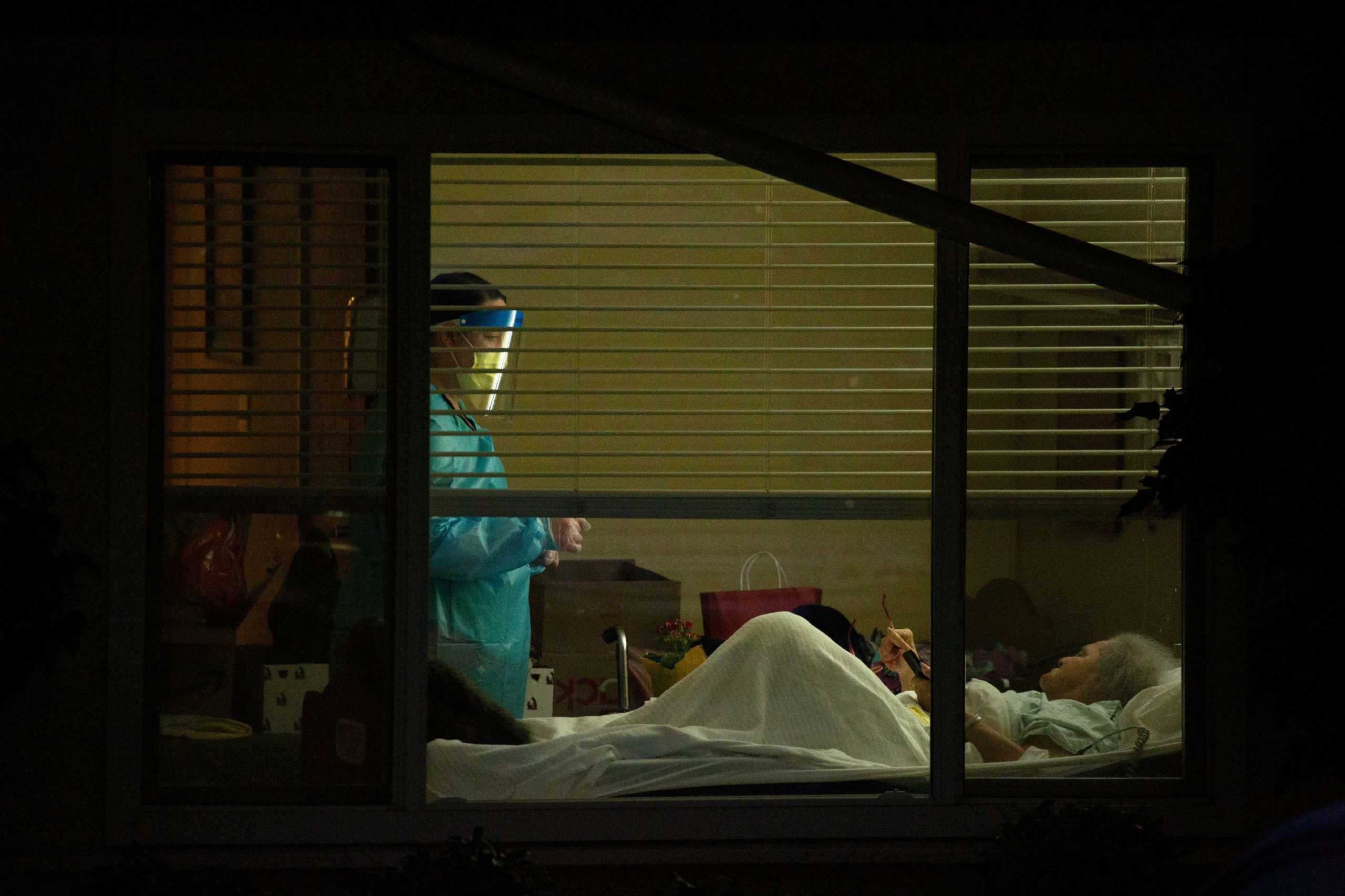 A healthcare worker attends to Susan Hailey, who has tested positive for coronavirus, at the Life Care Center of Kirkland, the Seattle-area nursing home at the epicenter of one of the biggest coronavirus outbreaks in the United States, in Kirkland, Washington, U.S. March 13, 2020.  REUTERS