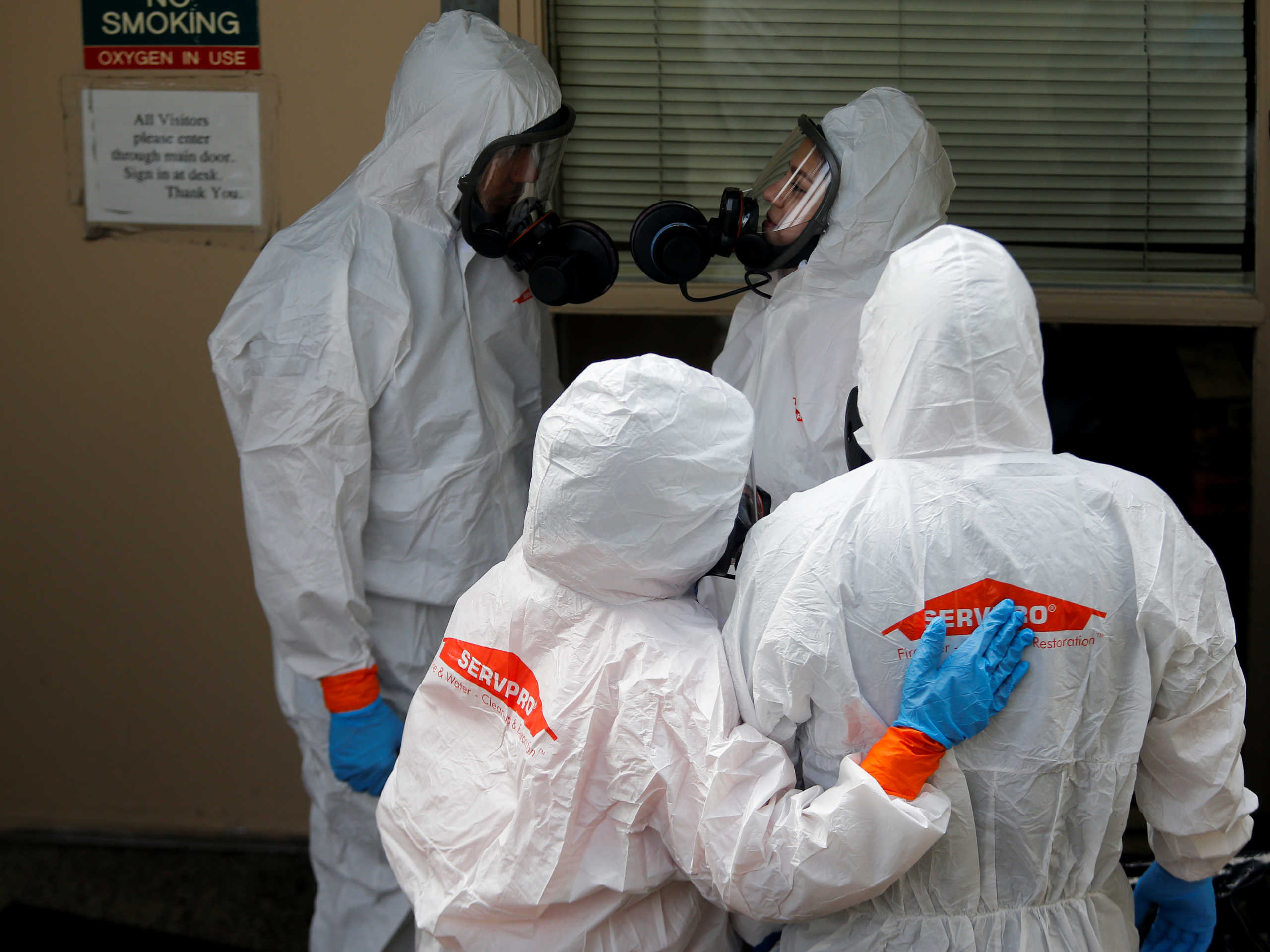 A Servpro worker hugs a coworker as they wait to enter Life Care Center of Kirkland, a long-term care facility linked to several confirmed coronavirus cases, in Kirkland, Washington, U.S., March 12, 2020.  REUTERS