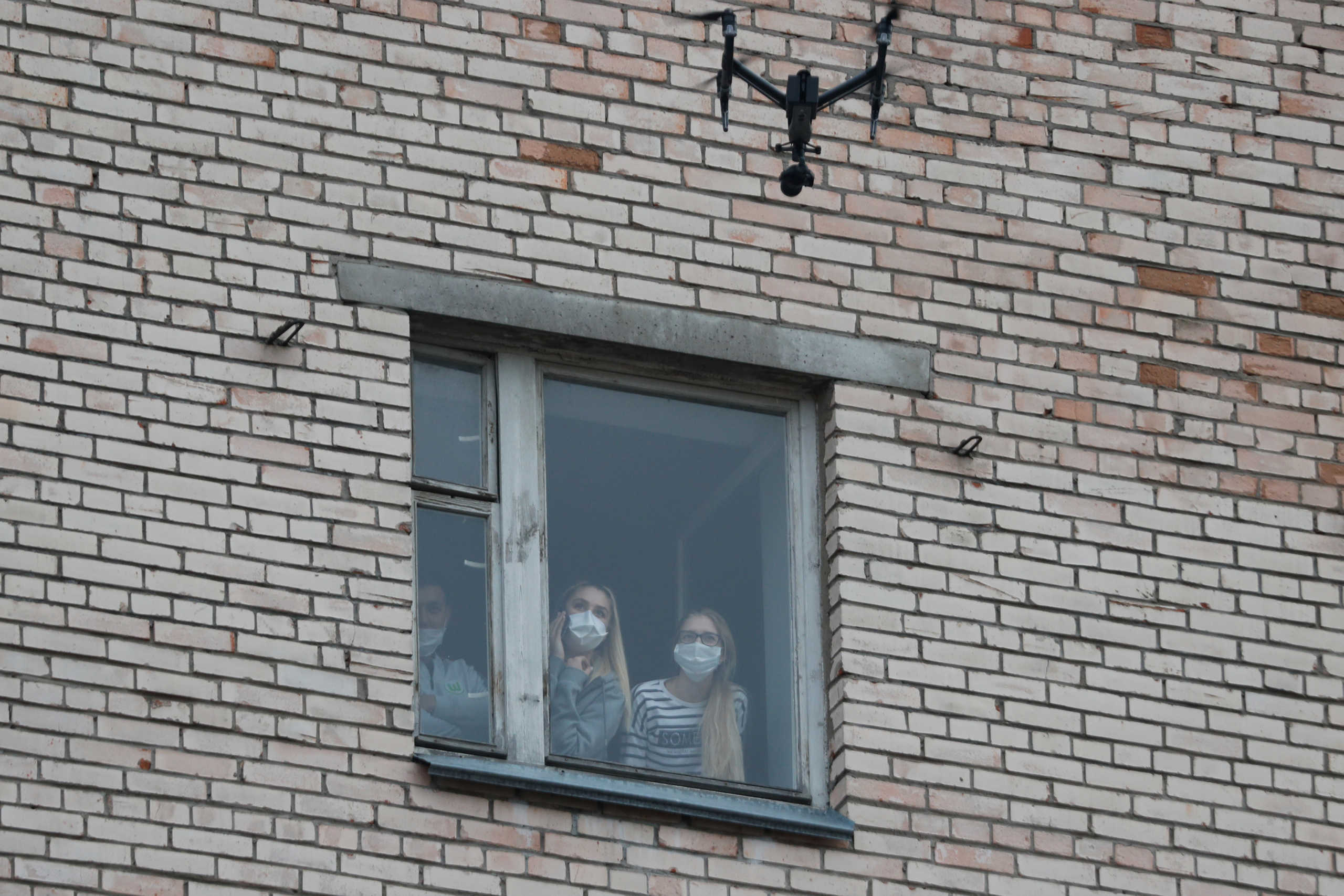 Students of the Mechnikov North-Western State Medical University wearing protective masks look out of a window of the dormitory where they placed under quarantine as part of precautions against the spread of coronavirus (COVID-19), after an Italian exchange student who returned to Russia tested positive for the virus, in Saint Petersburg, Russia March 8, 2020. REUTERS