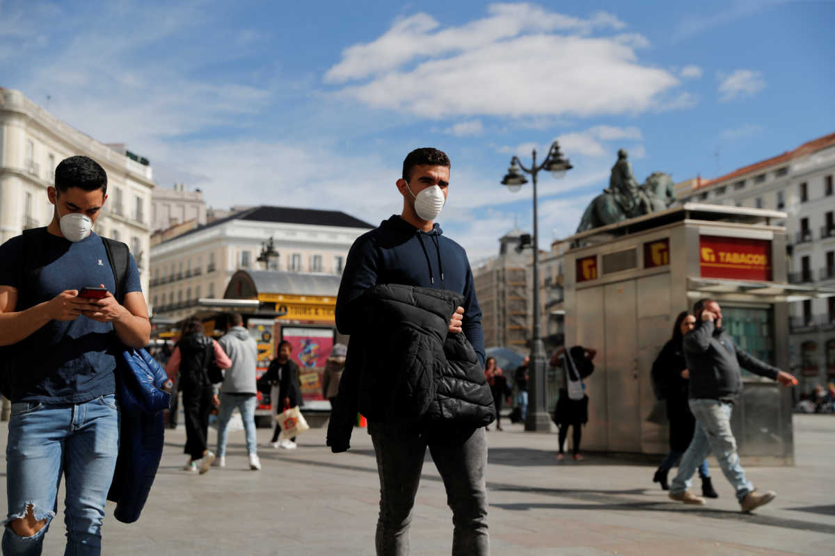Men wear protective masks as they walk through Puerta del Sol square in Madrid, Spain, March 4, 2020. REUTERS