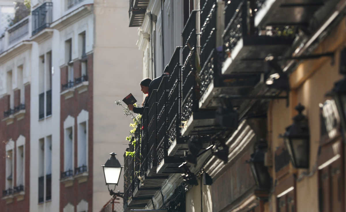 A woman reads a book on a balcony, during the coronavirus disease (COVID-19) outbreak, in Madrid, Spain, March 27, 2020. REUTERS
