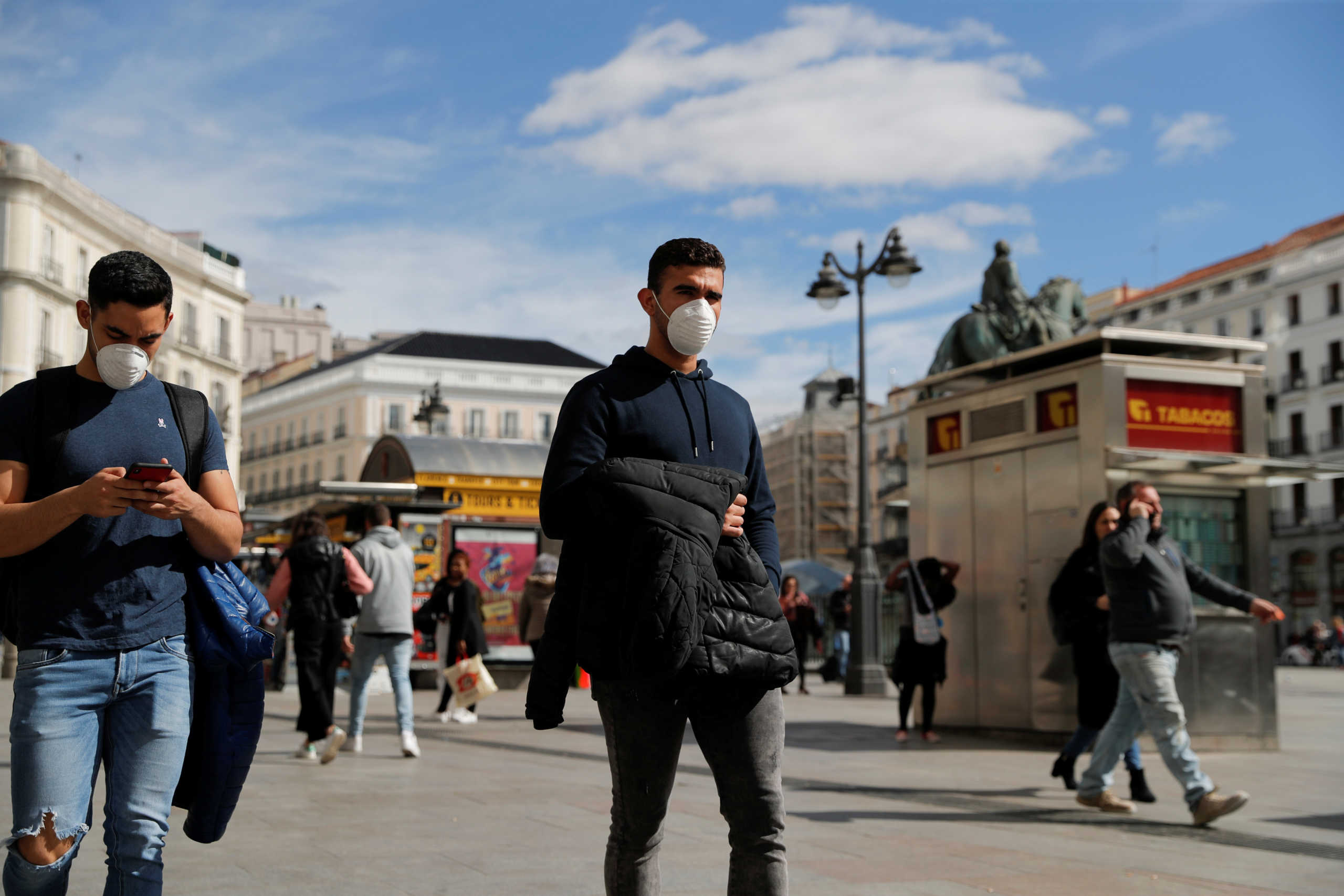 Men wear protective masks as they walk through Puerta del Sol square in Madrid, Spain, March 4, 2020. REUTERS