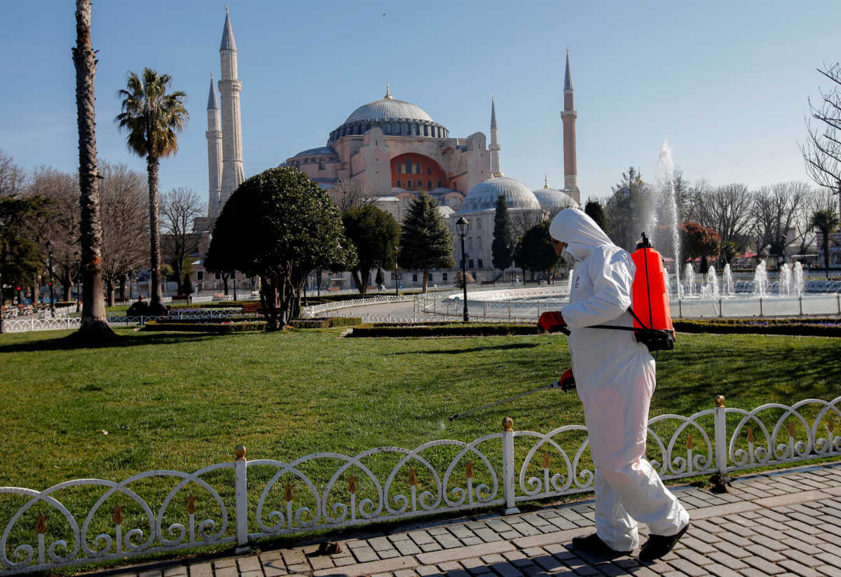 A worker in protective suit disinfects Sultanahmet square in response to the spread of coronavirus disease (COVID-19) in Istanbul,Turkey March 21, 2020. Byzantine-era monument of Hagia Sophia is seen in the background. REUTERS