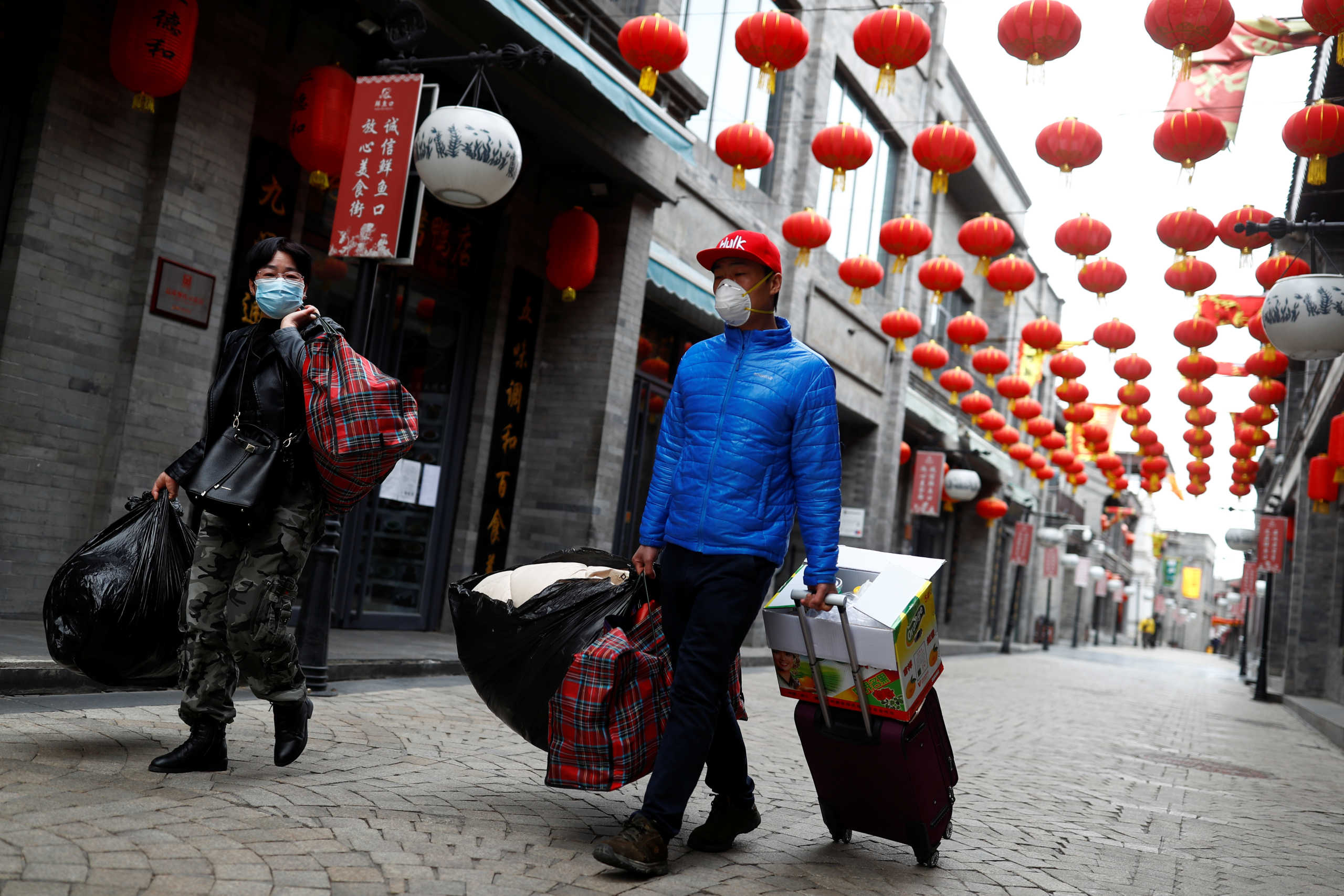 People wearing protective face masks walk in a historic district of Beijing, that is normally crowded with tourists, following the outbreak of coronavirus disease (COVID-19) in Beijing, China, March 26, 2020. REUTERS