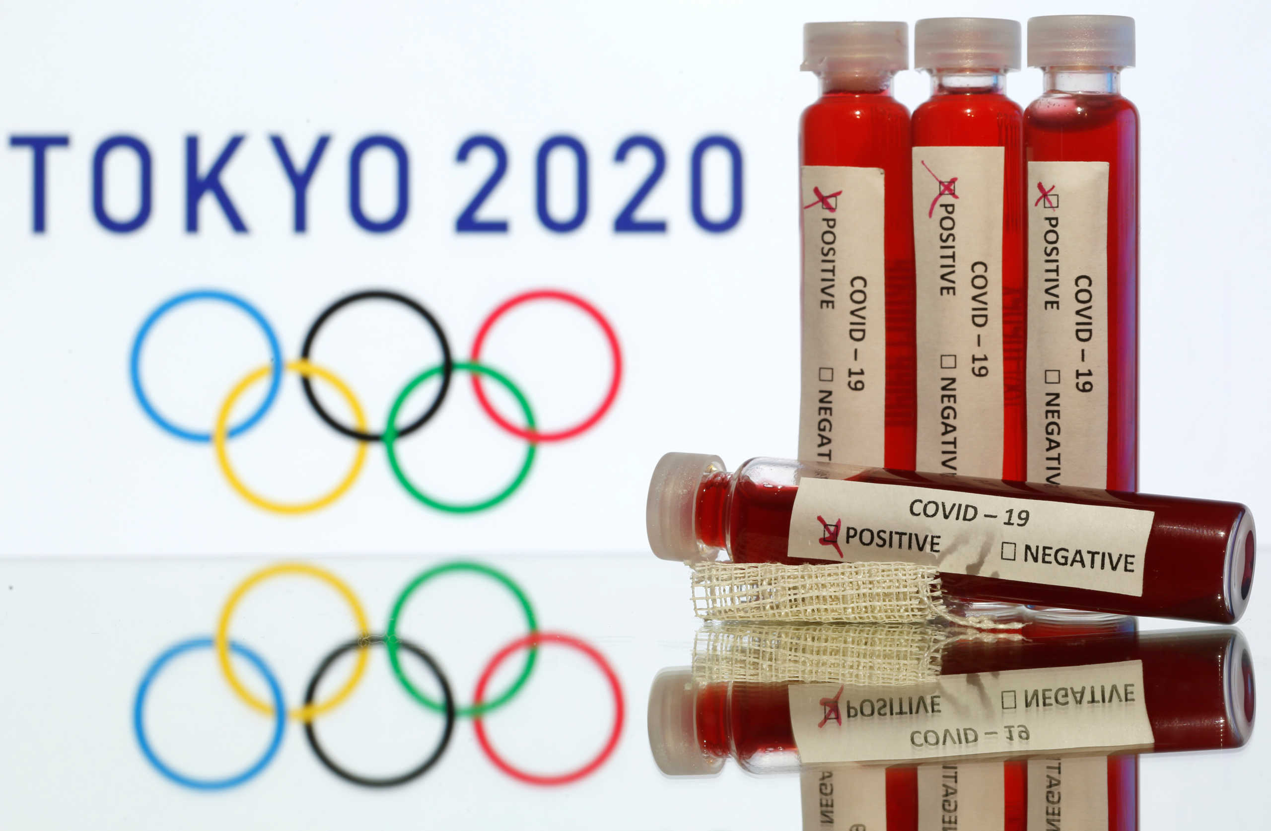 Fake blood in seen in test tubes labelled with coronavirus disease (COVID-19) in front of a displayed Tokyo 2020 Olympics logo in this illustration taken March 19, 2020. REUTERS
