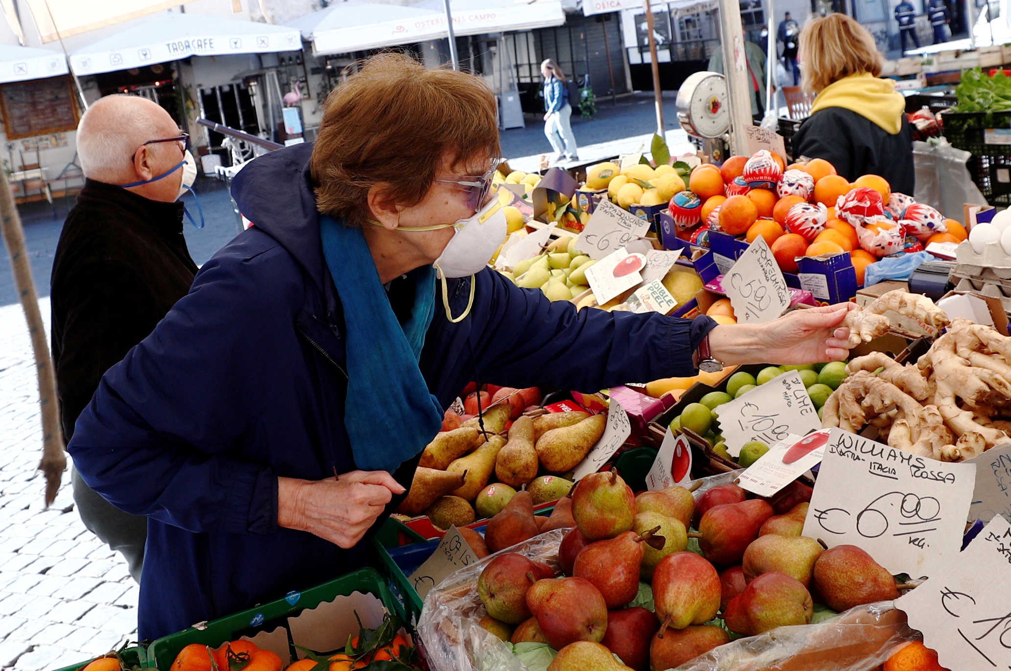 FILE PHOTO: A woman wears a protective face mask at Campo de' Fiori market on the second day of an unprecedented lockdown across all of the country, imposed to slow the outbreak of coronavirus, in Rome, Italy March 11, 2020. REUTERS