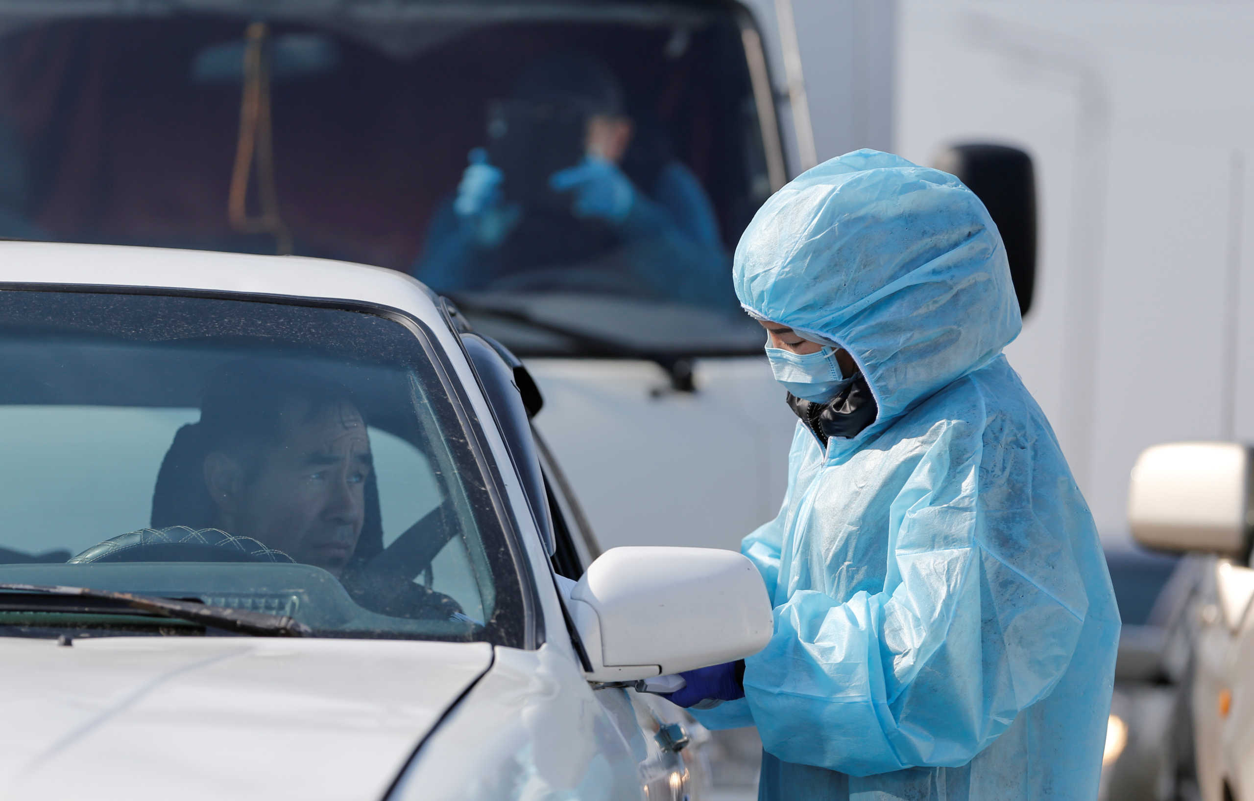An official wearing protective gear checks the documents of a driver, who waits in line to leave the city, following the Kazakh state emergency commission's decision to lock down Almaty to prevent the spread of coronavirus disease (COVID-19), at a check point on the outskirts of Almaty, Kazakhstan March 19, 2020. REUTERS