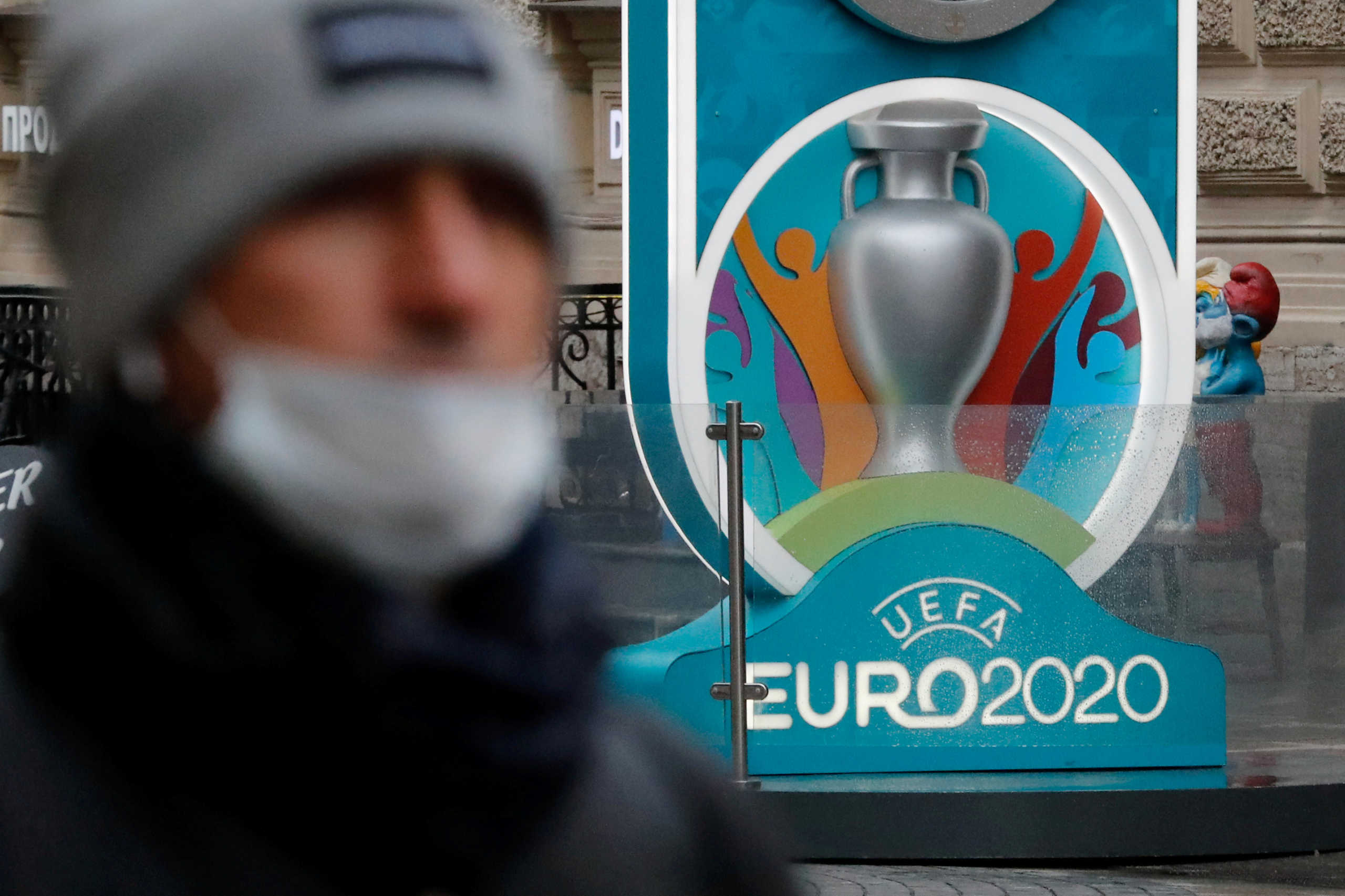 FILE PHOTO: A person wearing a protective face mask walks past the Euro 2020 countdown clock, as the number of coronavirus (COVID-19) cases worldwide continues to grow, in central Saint Petersburg, Russia March 16, 2020. REUTERS