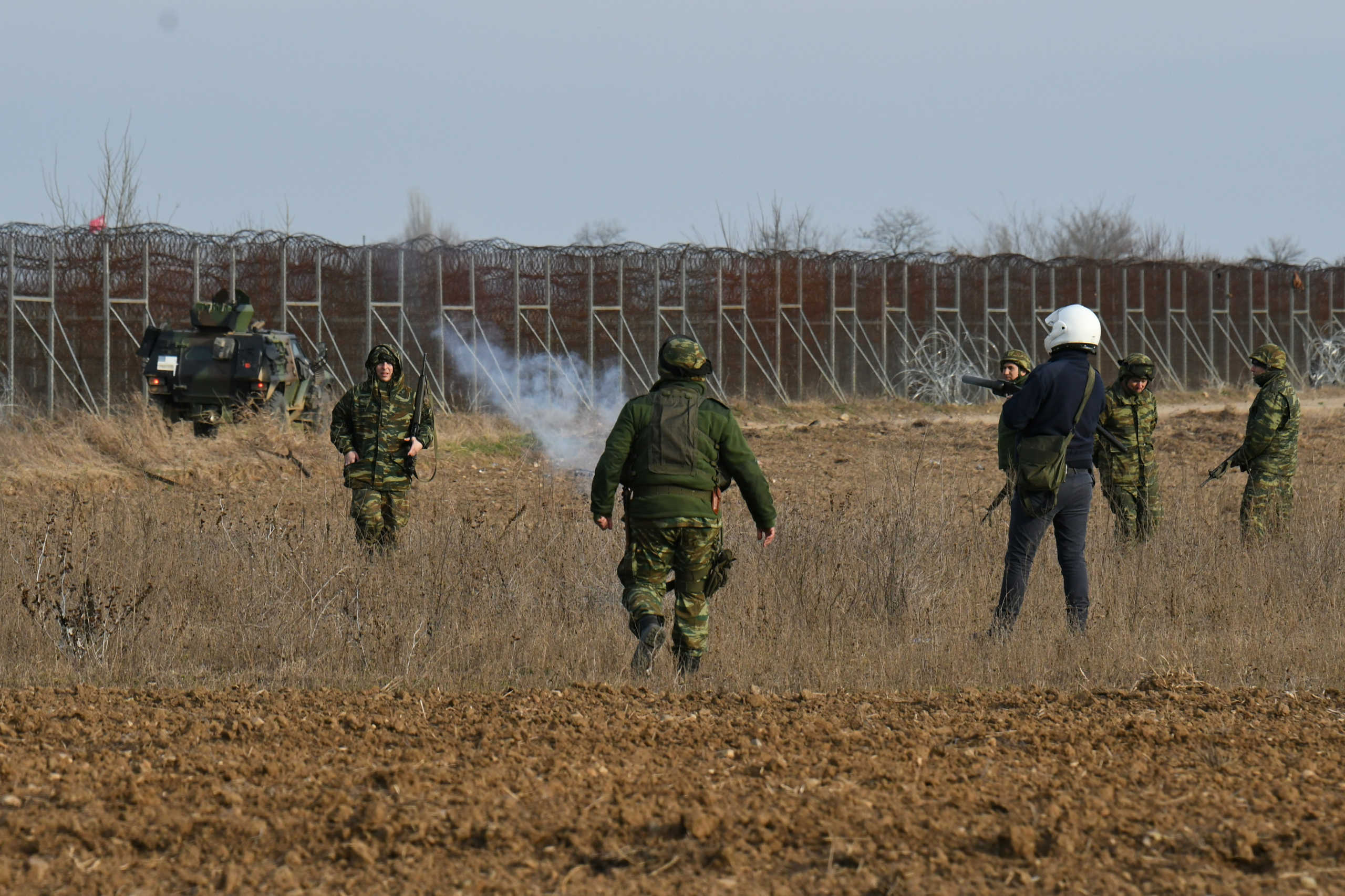 A police officer fires a tear gas canister with his launcher as Greek soldiers stand by, during clashes with migrants who want to cross into Greece from Turkey's Pazarkule border crossing, in Kastanies, Greece, March 1, 2020. REUTERS