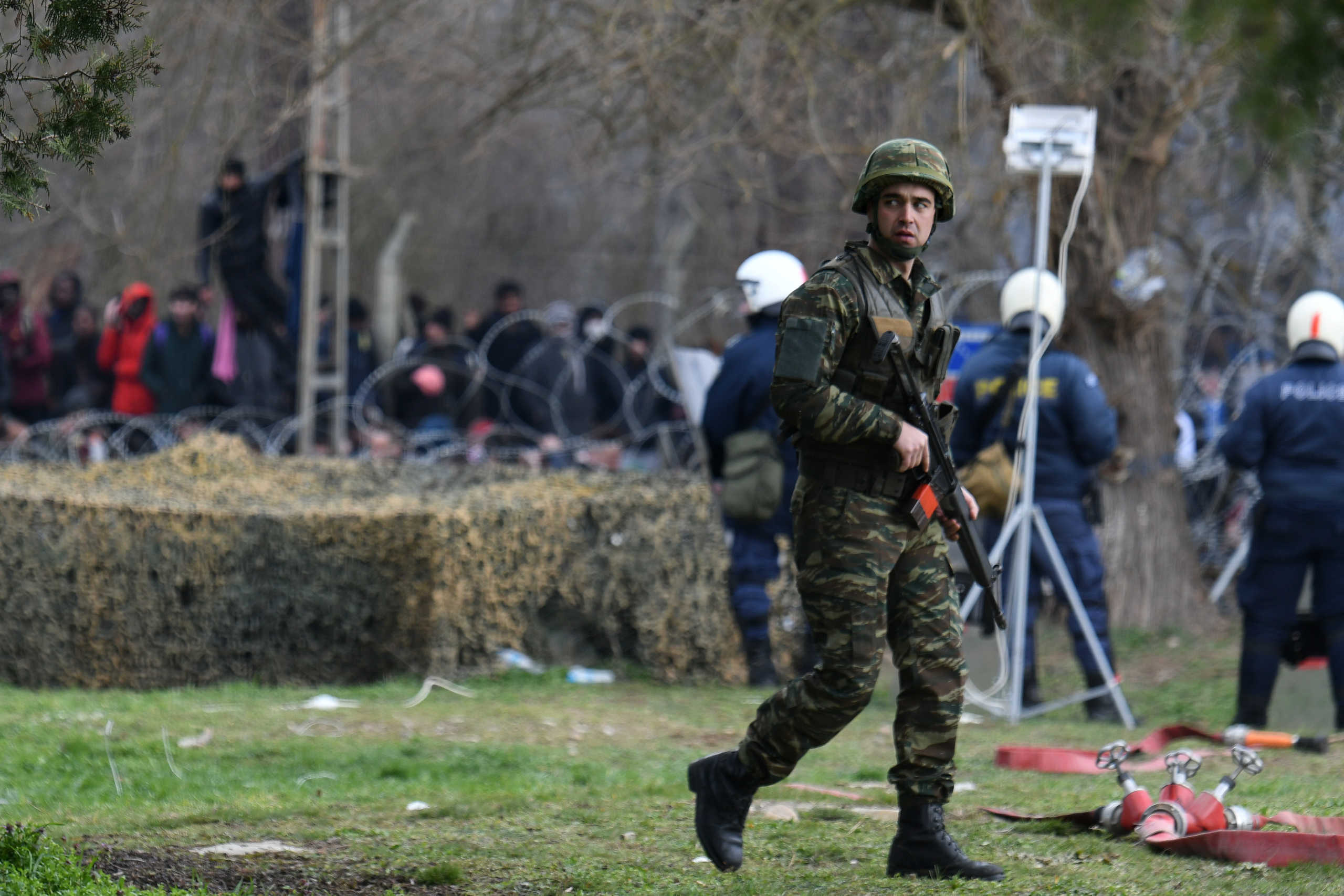 A Greek soldier patrols as migrants who want to cross into Greece from Turkey are gathered at the borderline, at the closed Kastanies border crossing with Turkey's Pazarkule, in the region of Evros, Greece, February 28, 2020. REUTERS