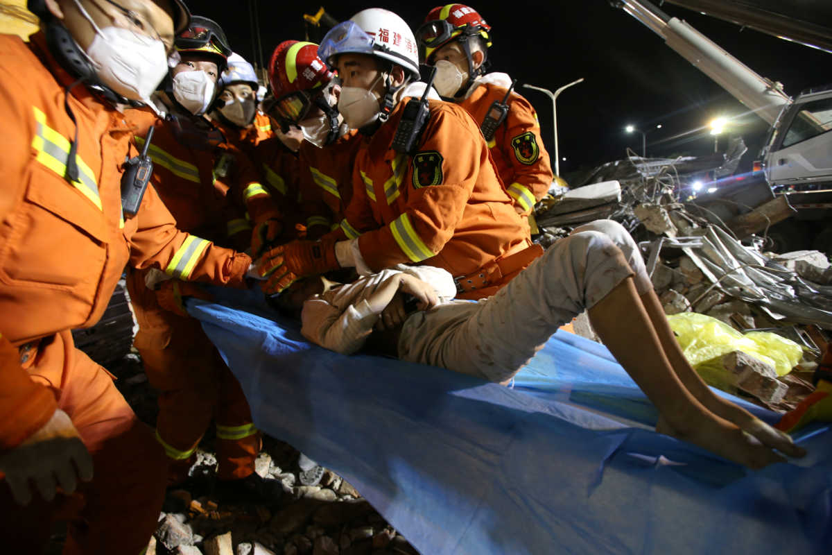 Rescue workers wearing face masks move a boy from the rubble of a collapsed hotel which has been used for medical observation following an outbreak of the novel coronavirus, in the southeast Chinese port city of Quanzhou, Fujian province, China March 9, 2020. Picture taken March 9, 2020. China Daily via REUTERS ATTENTION EDITORS - THIS IMAGE WAS PROVIDED BY A THIRD PARTY. CHINA OUT.