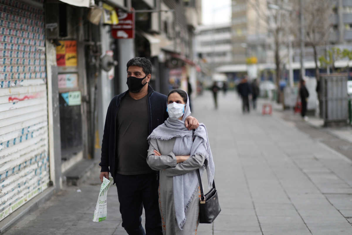 A couple wear protective face masks, amid fear of coronavirus disease (COVID-19), as they walk at Enghelab square, in Tehran, Iran March 26, 2020. WANA (West Asia News Agency)
