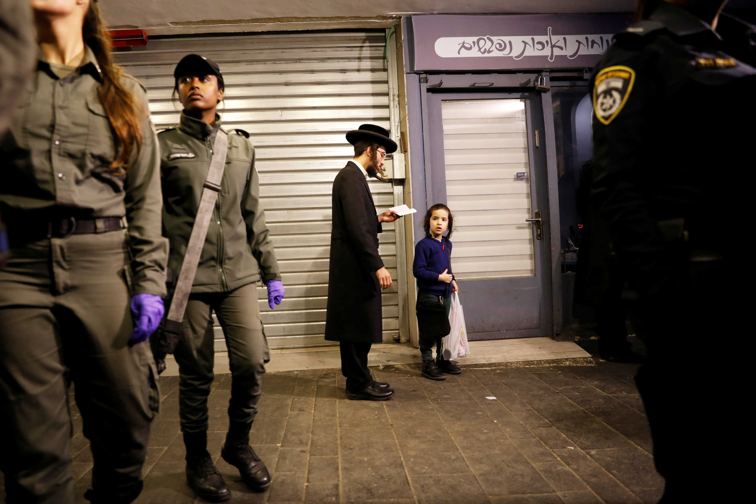 An ultra-Orthodox Jewish man prays next to shuttered shops as Israeli police officers enforce restrictions placed by the government to curb the coronavirus disease (COVID-19), in Mea Shearim neighborhood of Jerusalem March 25, 2020. REUTERS