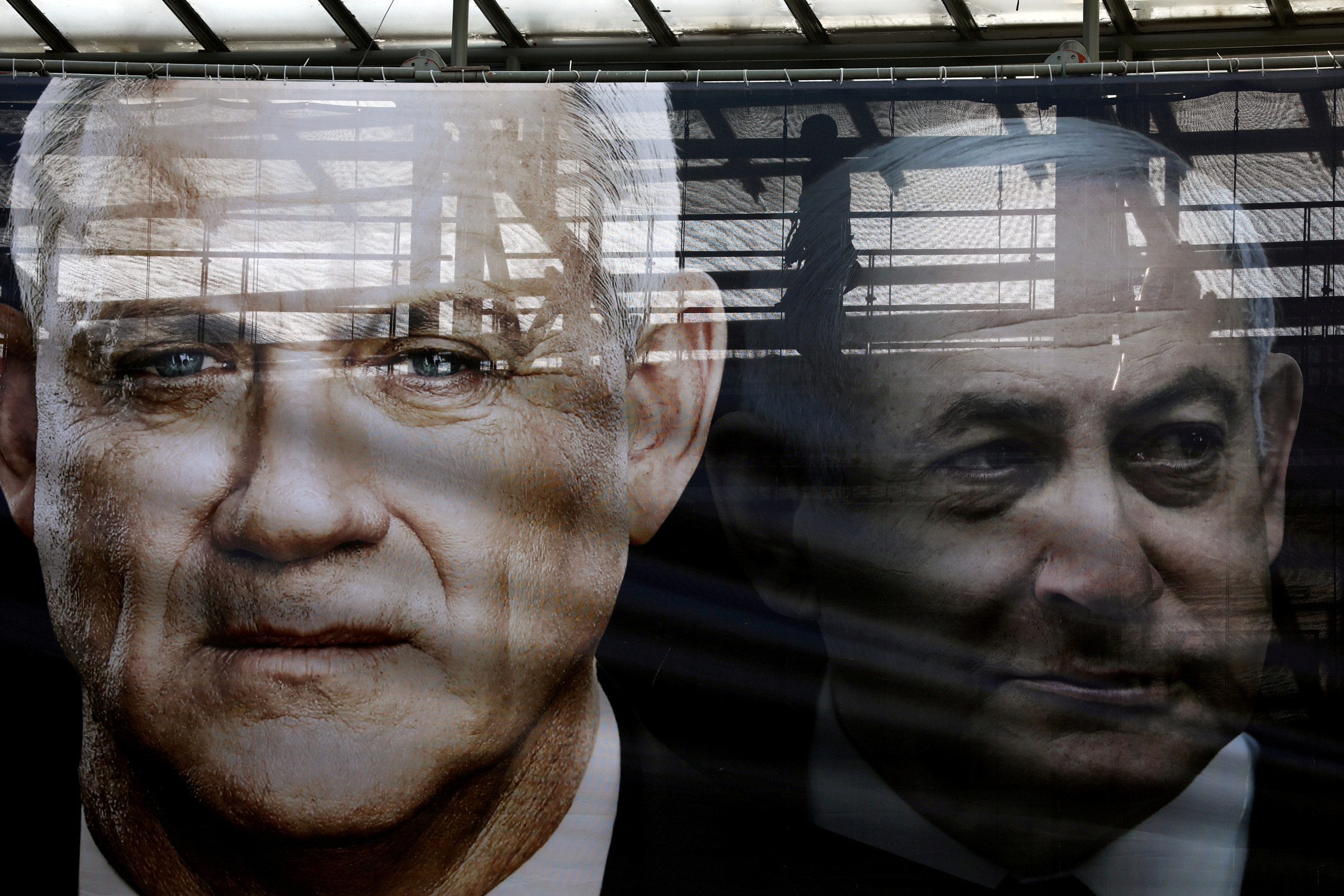 FILE PHOTO: A banner depicts Benny Gantz, leader of Blue and White party, and Israel Prime minister Benjamin Netanyahu, as part of Blue and White party's campaign ahead of the upcoming election, in Tel Aviv, Israel February 17, 2020. REUTERS
