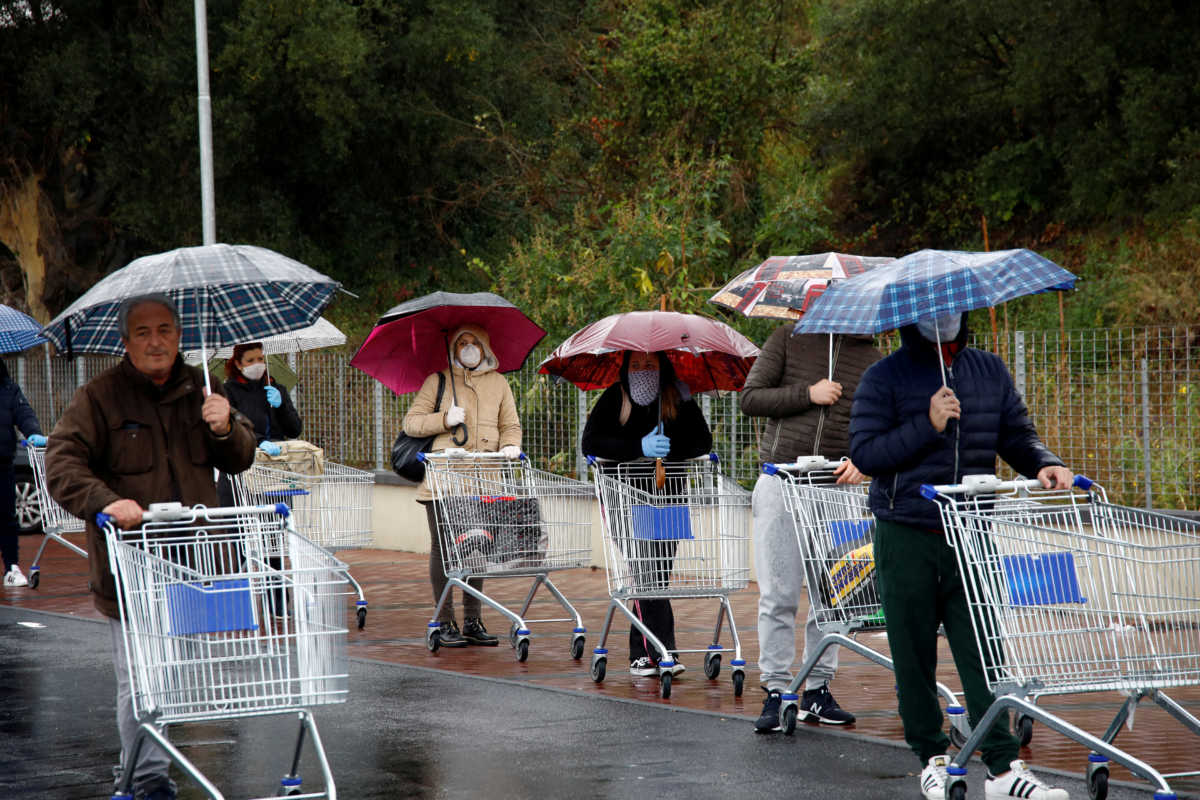 People line up in the rain outside a supermarket after the Italian island of Sicily closed them on Sunday, as it tightens measures to try and contain the spread of coronavirus disease (COVID-19), in Catania, Italy March 23, 2020. REUTERS