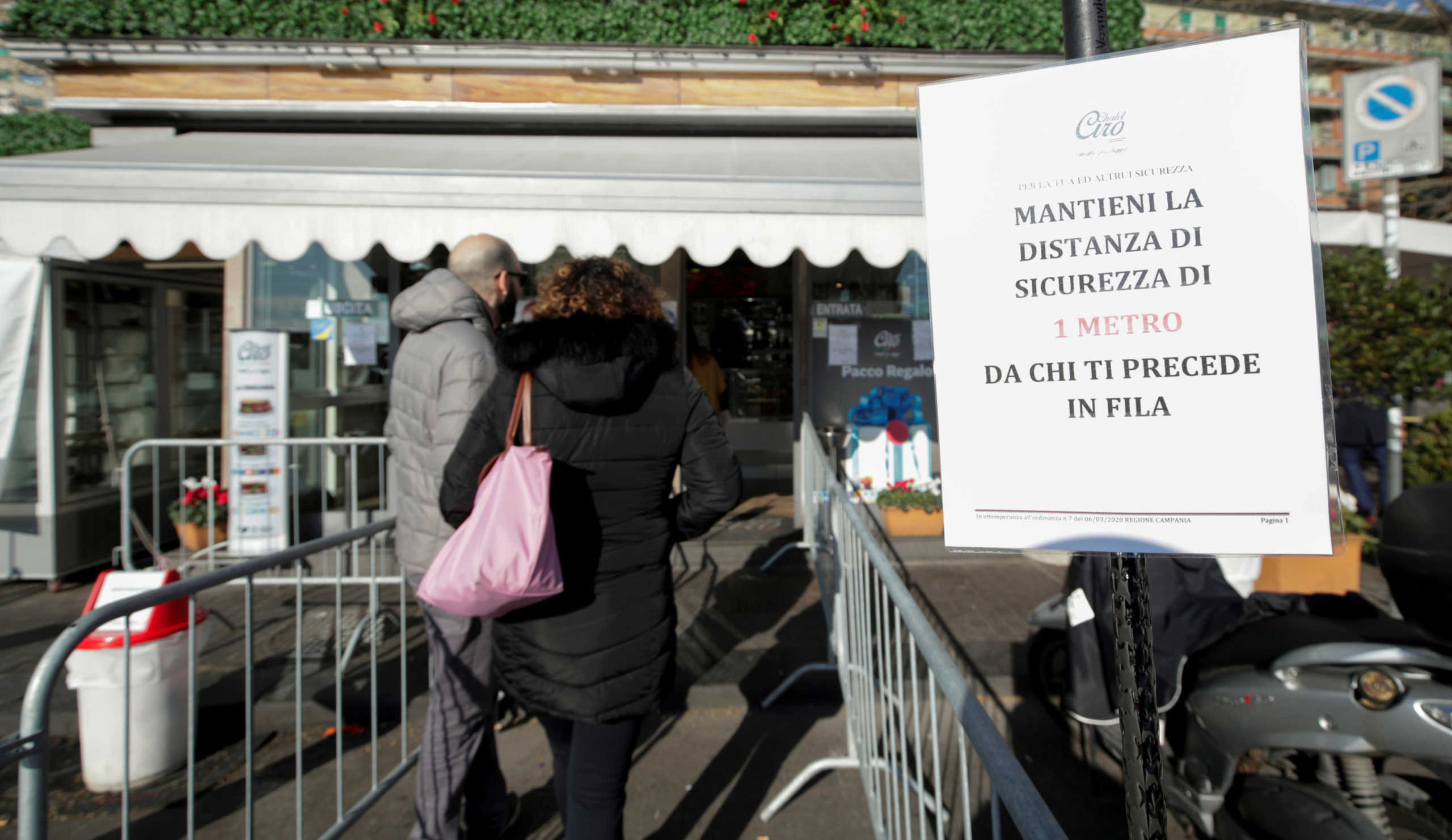 People wait outside a supermarket after a decree orders for the whole of Italy to be on lockdown in an unprecedented clampdown aimed at beating the coronavirus, in Naples, Italy, March 10, 2020. The banner reads: "Maintain a safe distance of 1 meter from those who are in front of you." REUTERS