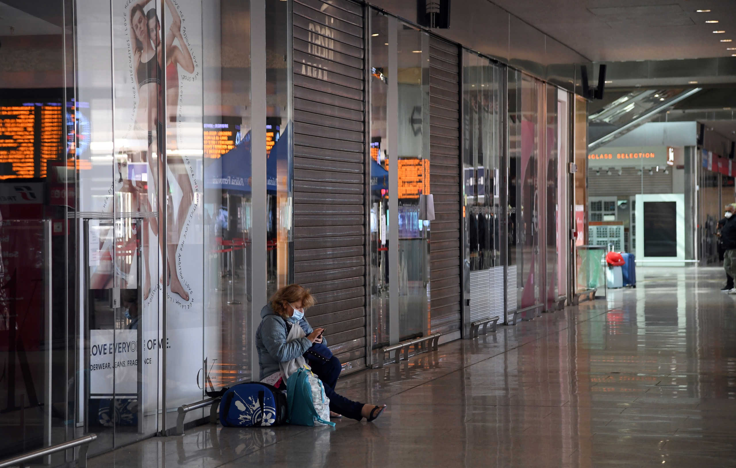 A woman checks her phone, as Italy tightens measures to try and contain the spread of coronavirus disease (COVID-19), at Rome's Termini train station, Italy March 23, 2020. REUTERS