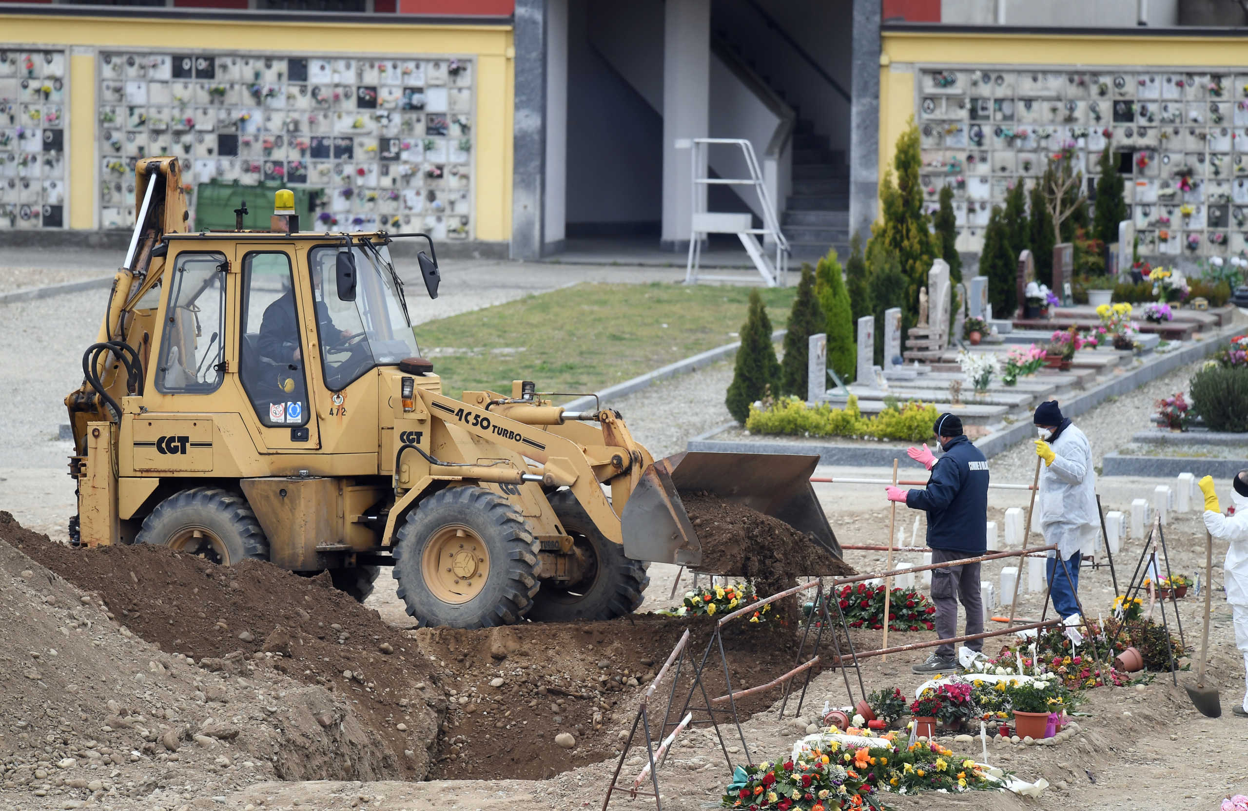 Workers dig a hole at a cemetery, as the spread of the coronavirus disease (COVID-19) continues, in Milan, Italy March 23, 2020. REUTERS