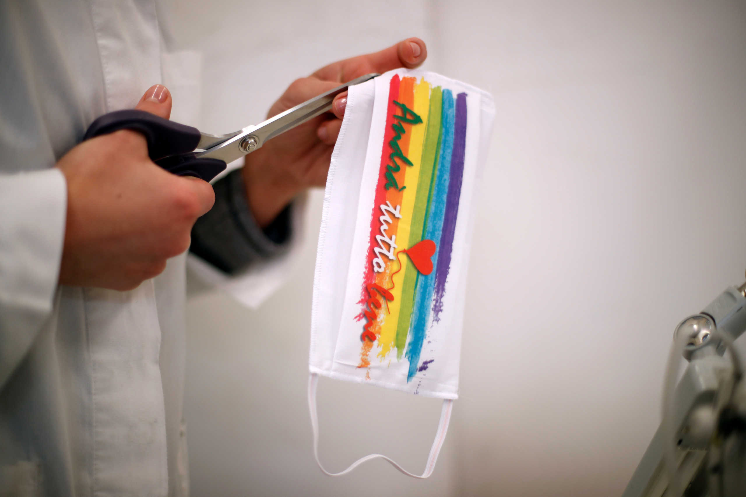 An employee works on a protective face mask with the phrase 'andra tutto bene' that means 'everything will be ok', sewn onto it - a phrase that has a symbol of hope as Italy battles a spread of coronavirus disease (COVID-19), in a clothing factory of sisters Barbara, Lisa and Manuela De Virgilio, that usually makes women's fashionwear but now makes solely face masks, in Molfetta, southern Italy, March 25, 2020. REUTERS