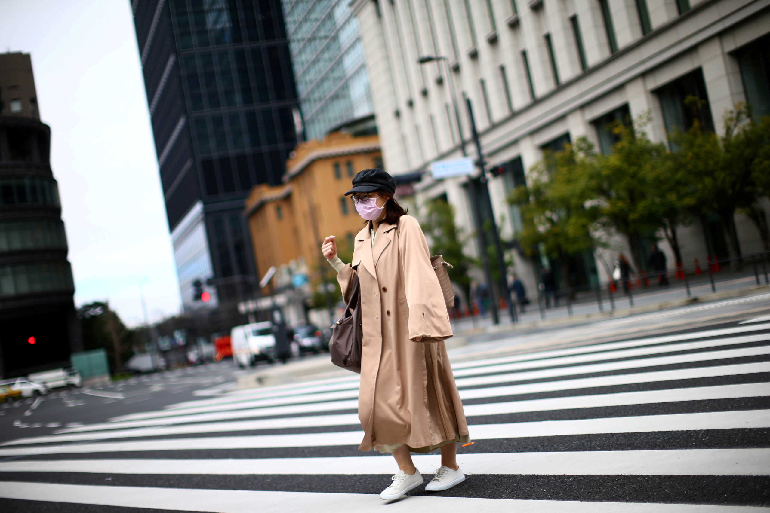 FILE PHOTO: A woman, wearing protective face masks following an outbreak of the coronavirus disease (COVID-19), walks on a street in Tokyo, Japan March 9, 2020. REUTERS