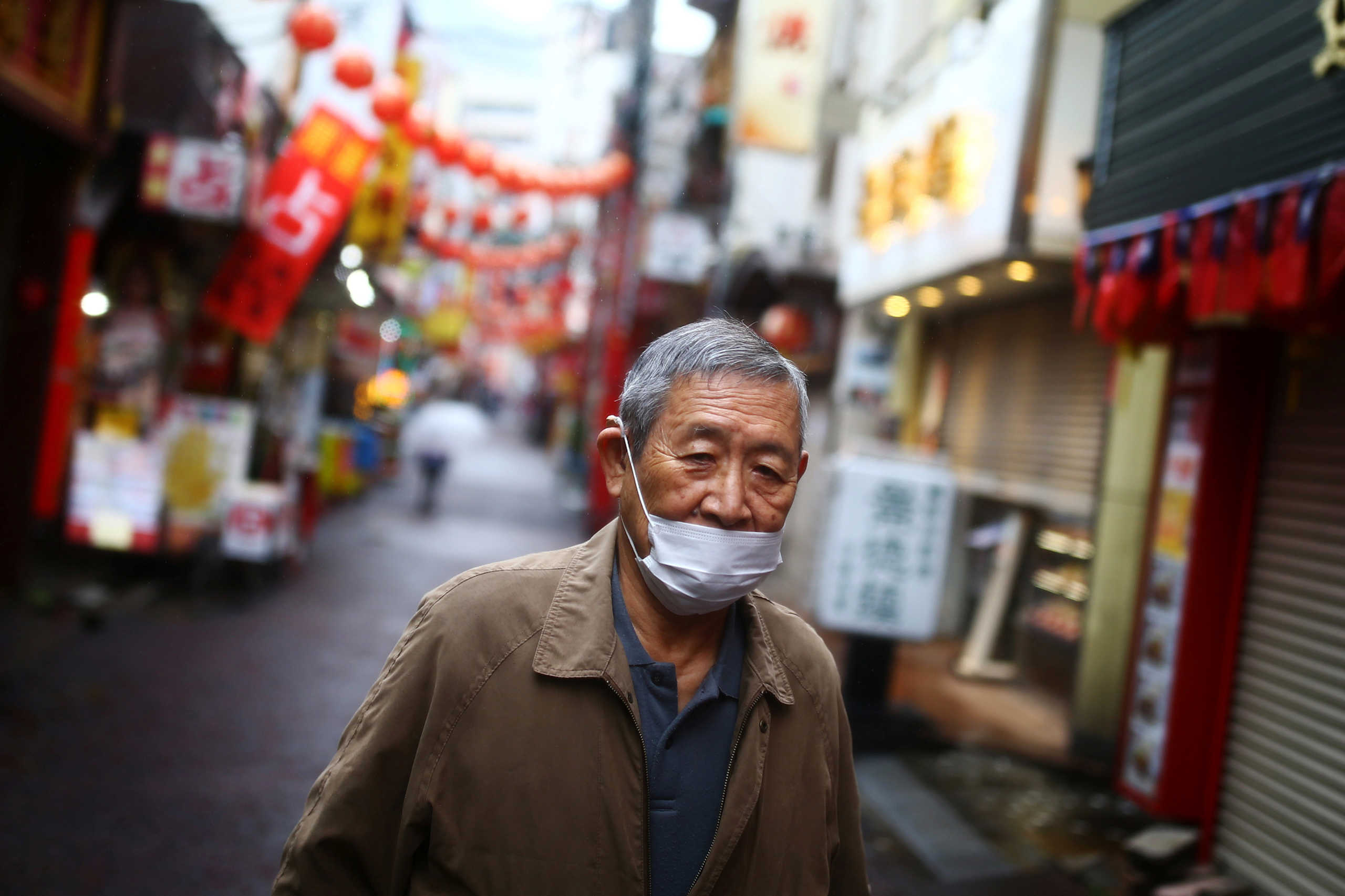 A man, wearing protective mask following an outbreak of the coronavirus disease (COVID-19), walks on an almost empty street in Yokohama?s Chinatown, south of Tokyo, Japan March 10, 2020. Picture taken, March, 10,2020. REUTERS