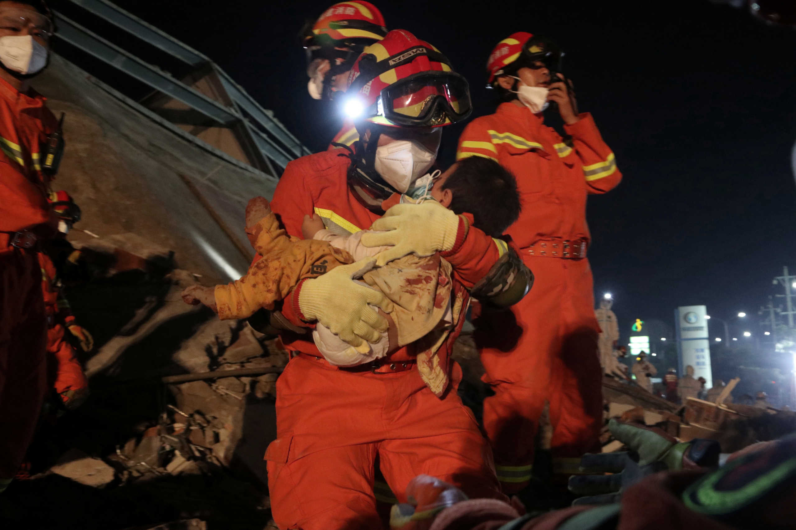 A worker wearing a face mask rescues a child at the site where a hotel being used for the coronavirus quarantine collapsed, in the southeast Chinese port city of Quanzhou, Fujian province, China March 8, 2020. China Daily via REUTERS ATTENTION EDITORS - THIS IMAGE WAS PROVIDED BY A THIRD PARTY. CHINA OUT.