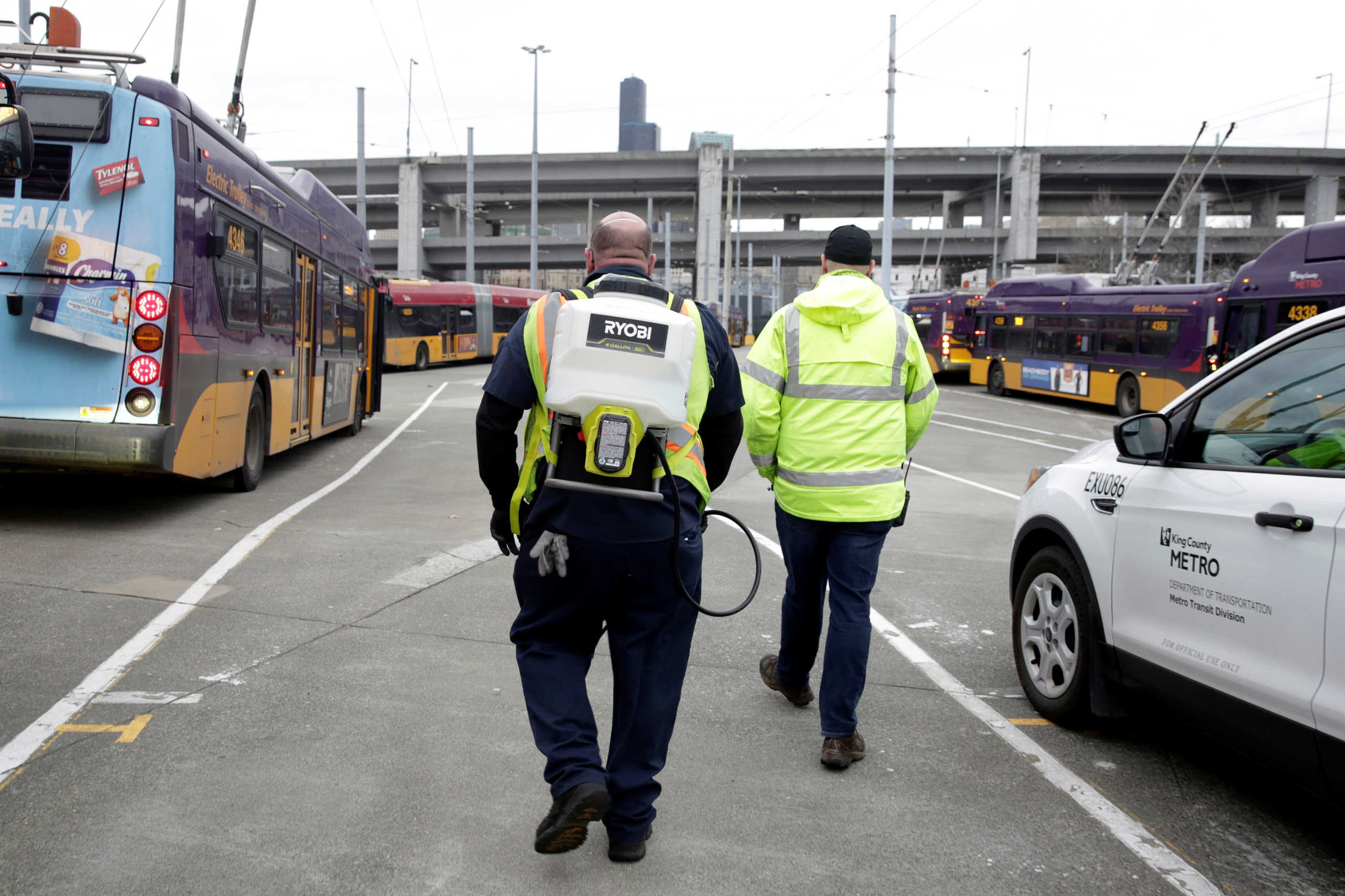 Raymond Determann (L), a King County Metro equipment service worker, wears a backpack that sprays a Virex solution to sanitize buses against the coronavirus in Seattle, Washington, U.S. March 5, 2020.  REUTERS