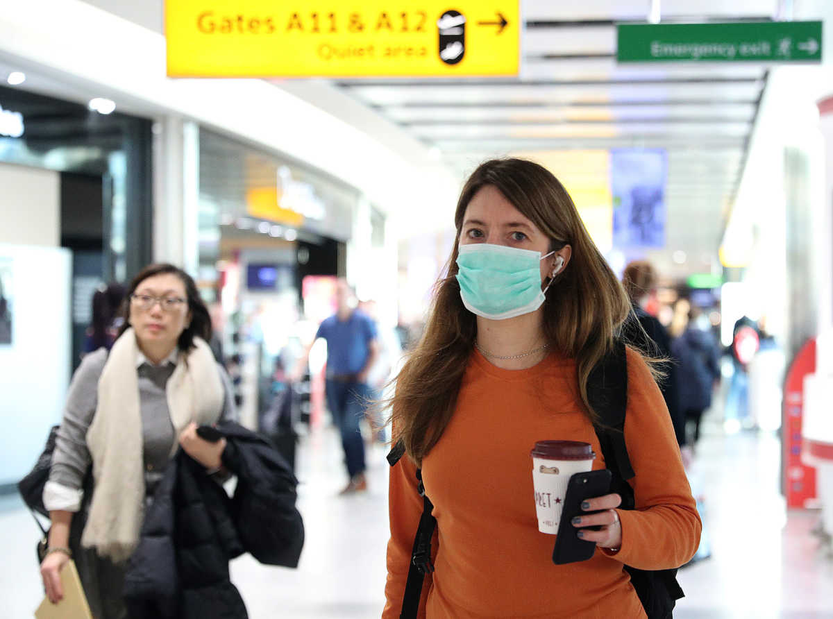 A woman wears a surgical mask as she walks through Terminal 5 at Heathrow Airport in London, Britain March 6, 2020. REUTERS