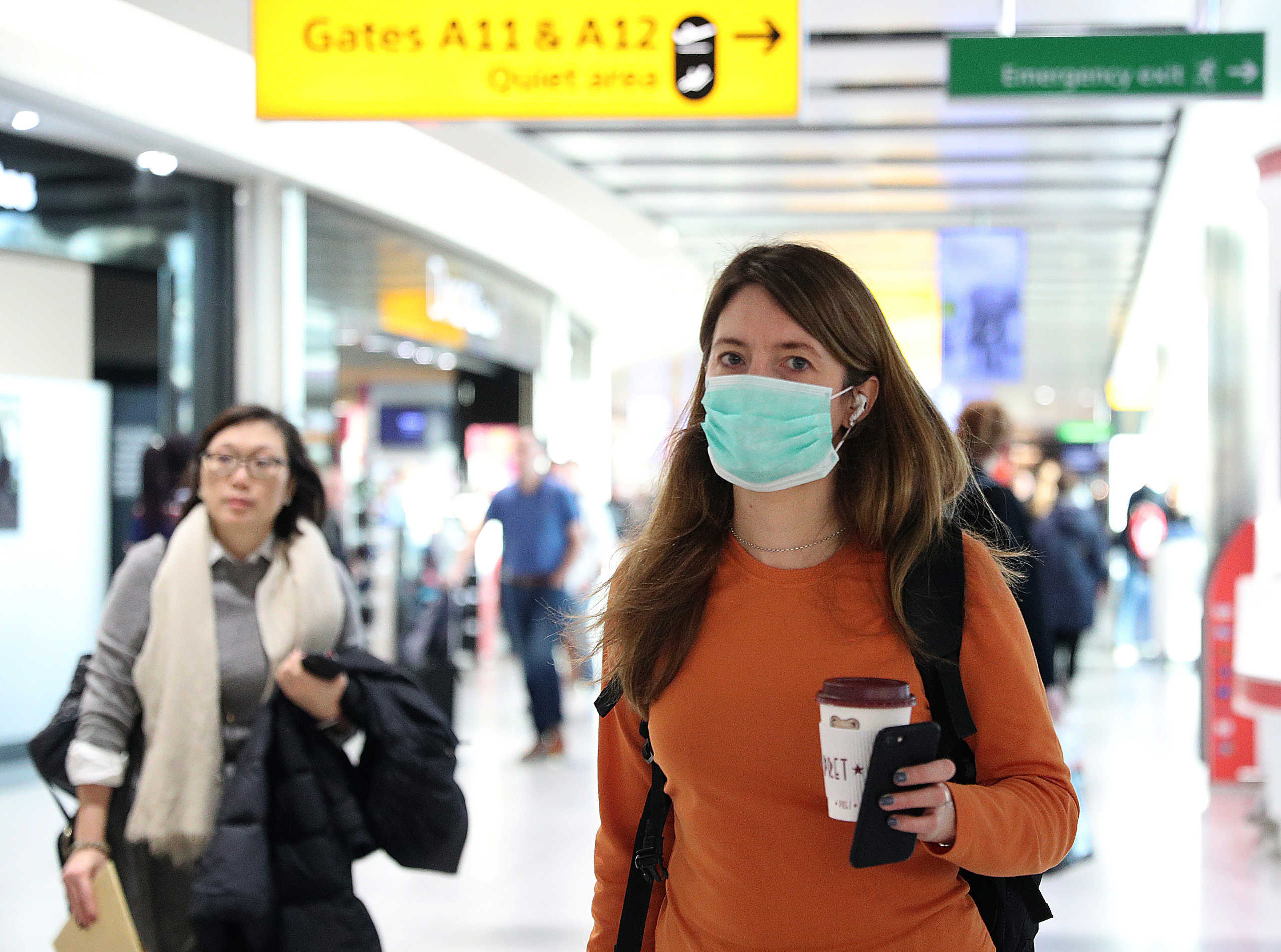 A woman wears a surgical mask as she walks through Terminal 5 at Heathrow Airport in London, Britain March 6, 2020. REUTERS