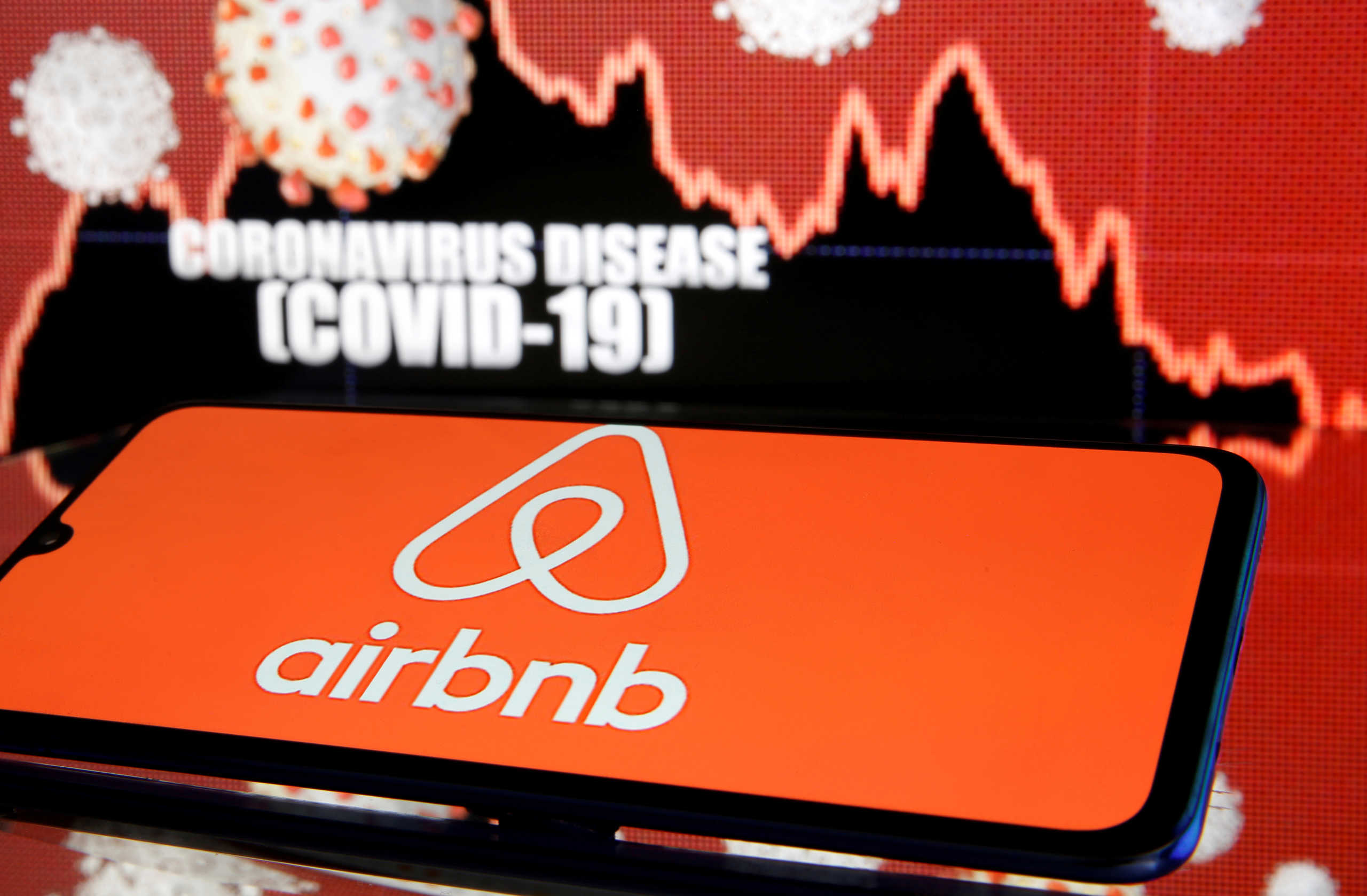 FILE PHOTO: Airbnb logo is seen in front of diplayed coronavirus disease (COVID-19) in this illustration taken March 19, 2020. REUTERS