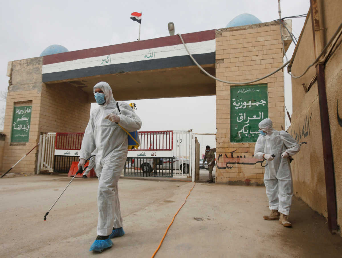 Workers in protective suits spray disinfectants near the gate of Shalamcha Border Crossing, after Iraq shut a border crossing to travellers between Iraq and Iran, Iraq March 8, 2020. REUTERS