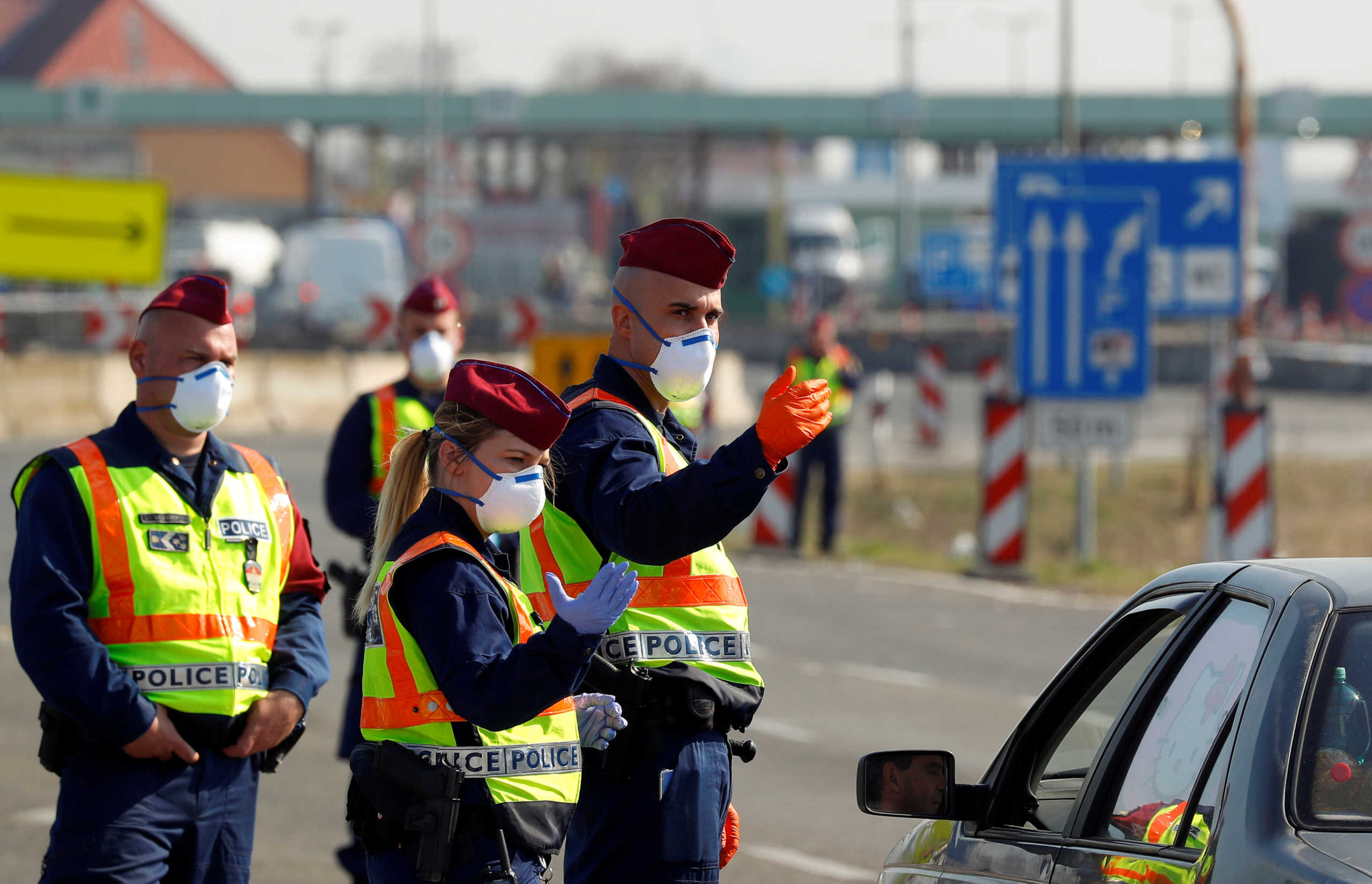 FILE PHOTO: Hungarian police officers gesture while the Hungarian-Austrian border is closed, as the spread of the coronavirus disease (COVID-19) continues, near Nickelsdorf, Austria, March 18, 2020. REUTERS