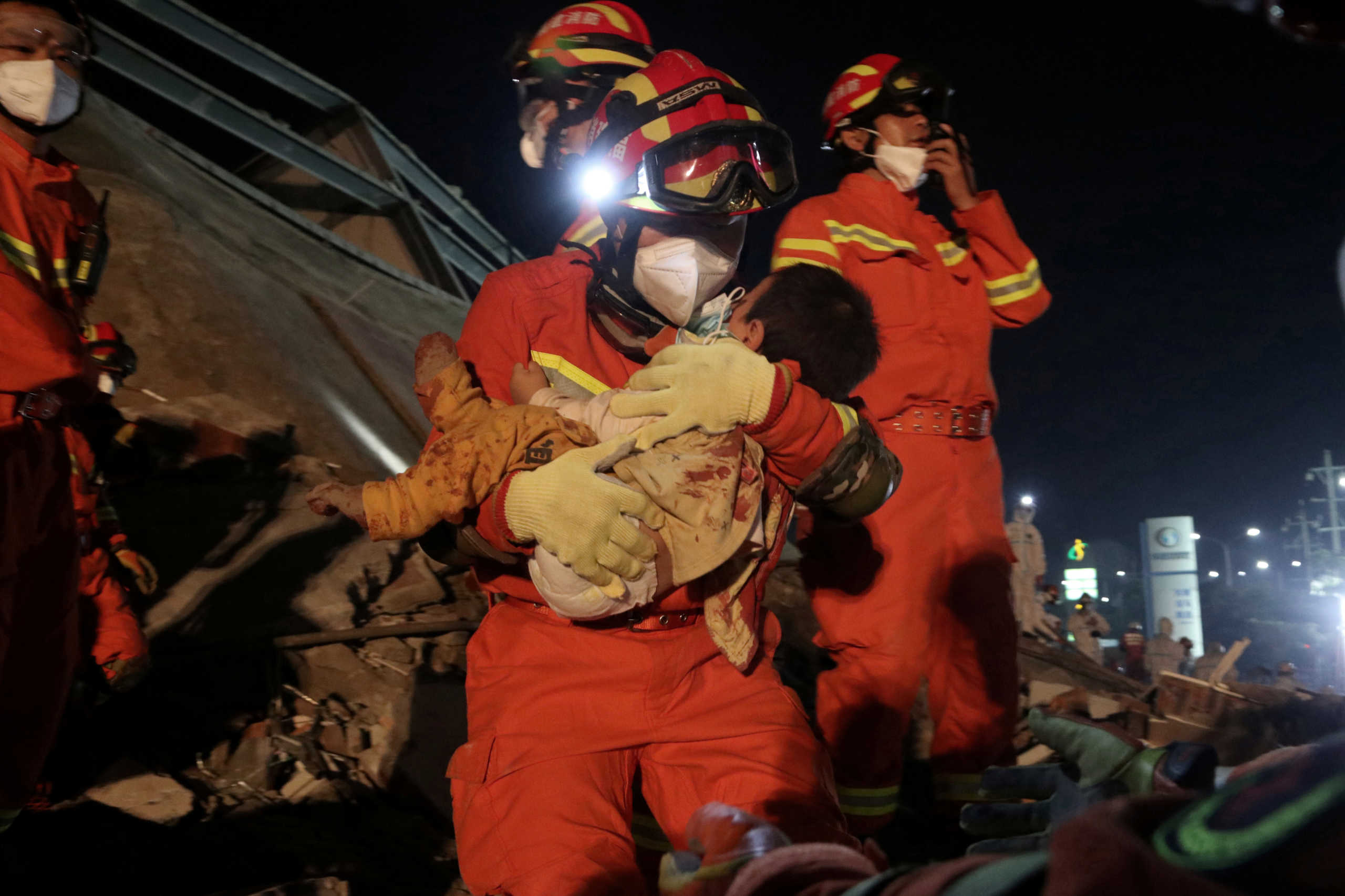A worker wearing a face mask rescues a child at the site where a hotel being used for the coronavirus quarantine collapsed, in the southeast Chinese port city of Quanzhou, Fujian province, China March 8, 2020. China Daily via REUTERS ATTENTION EDITORS - THIS IMAGE WAS PROVIDED BY A THIRD PARTY. CHINA OUT.     TPX IMAGES OF THE DAY