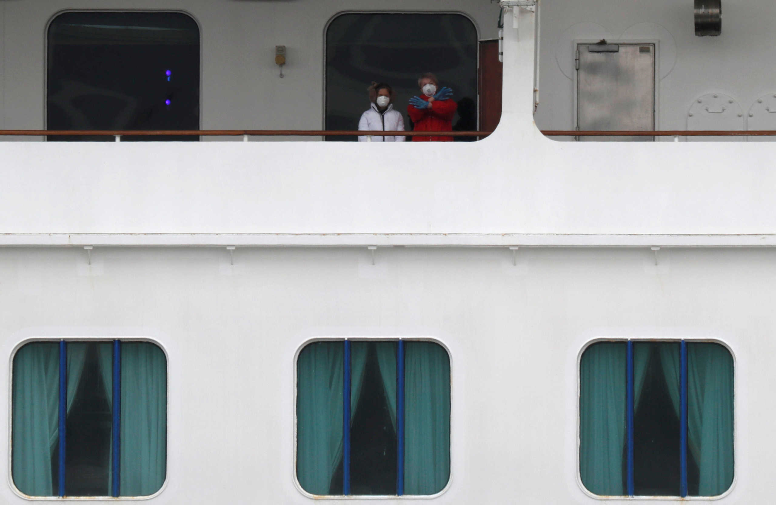 Masked passengers react from on board the coronavirus-hit Diamond Princess cruise ship docked at Yokohama Port, south of Tokyo, Japan, February 20, 2020. REUTERS