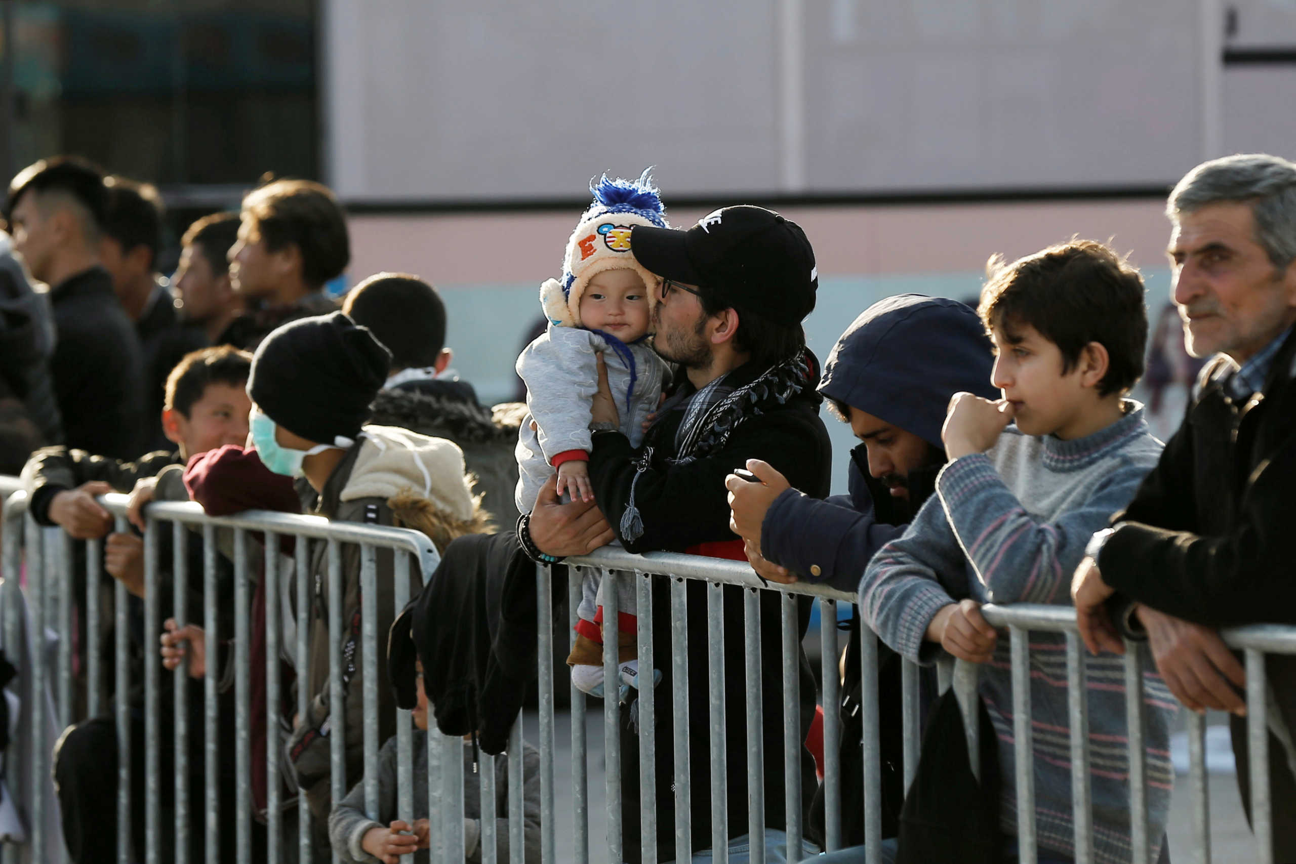A man kisses a child as migrants who arrived on the island of Lesbos in the past three days, are seen at the port of Mytilene, where they are sheltered, Greece, March 3, 2020. REUTERS