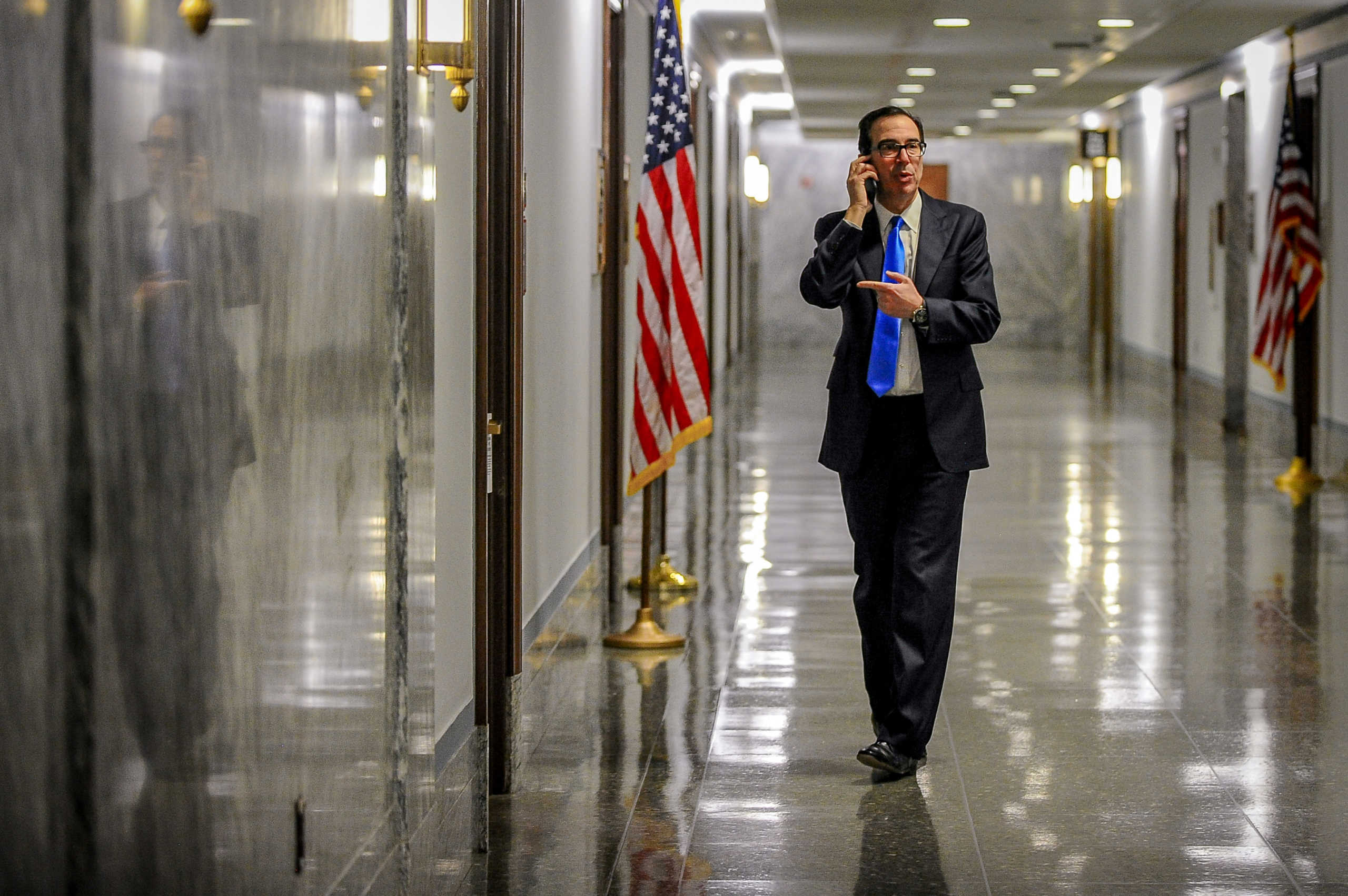 Treasury Secretary Steve Mnuchin takes a phone call in the hall outside a meeting to wrap up work on coronavirus economic aid legislation to prevent the spread of coronavirus disease (COVID-19) in Washington, U.S., March 21, 2020.      REUTERS