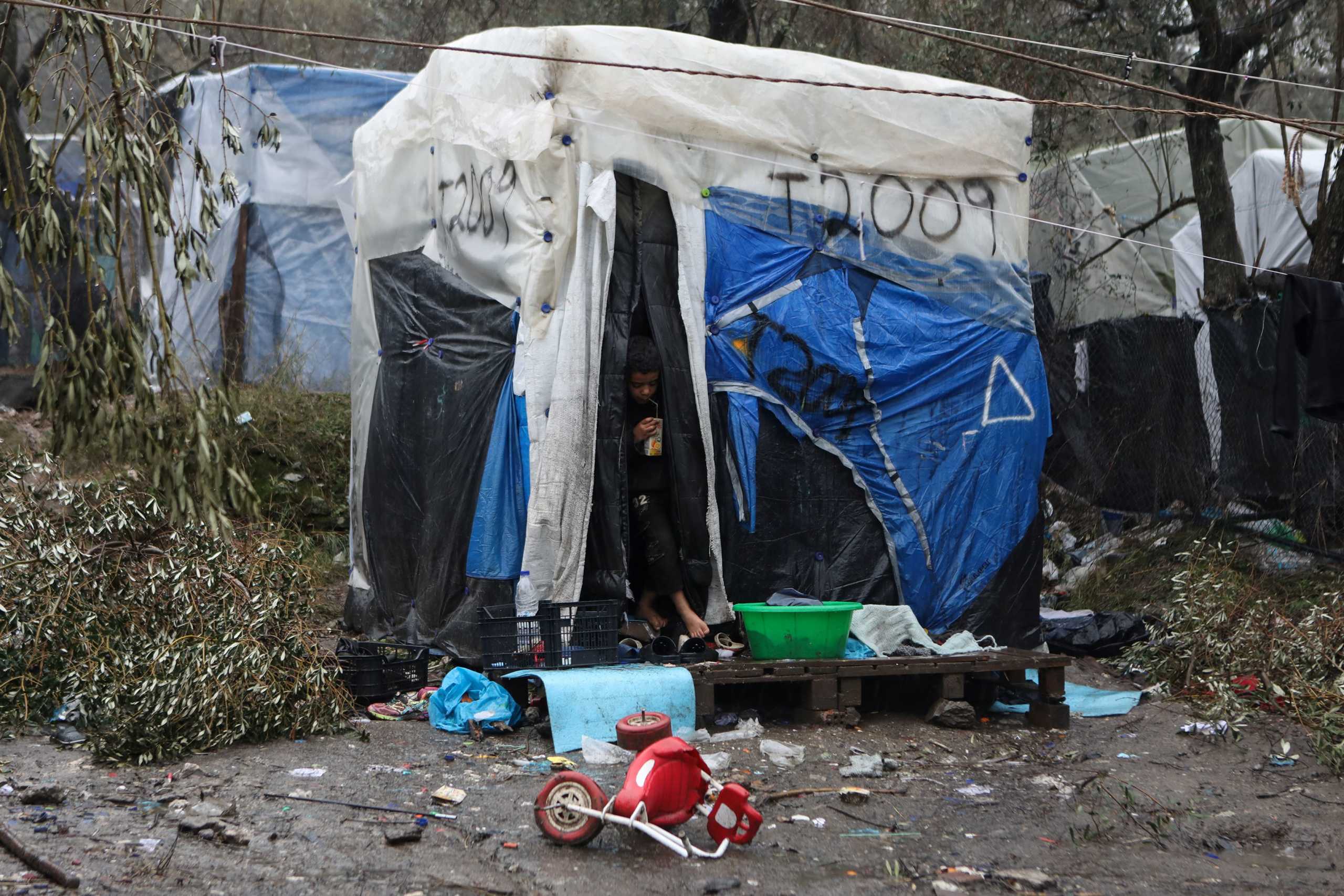 A boy is seen at the entrance of a temporary shelter at a camp for refugees and migrants next to the Moria camp on the island of Lesbos, Greece, February 6, 2020. REUTERS
