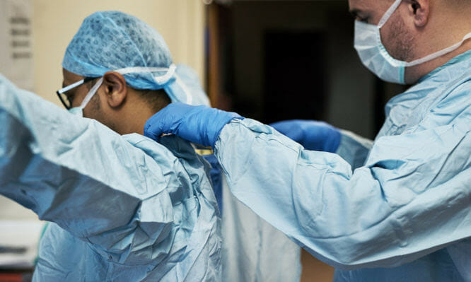 Shot of two surgeons helping each other get dressed in preparation for a surgery