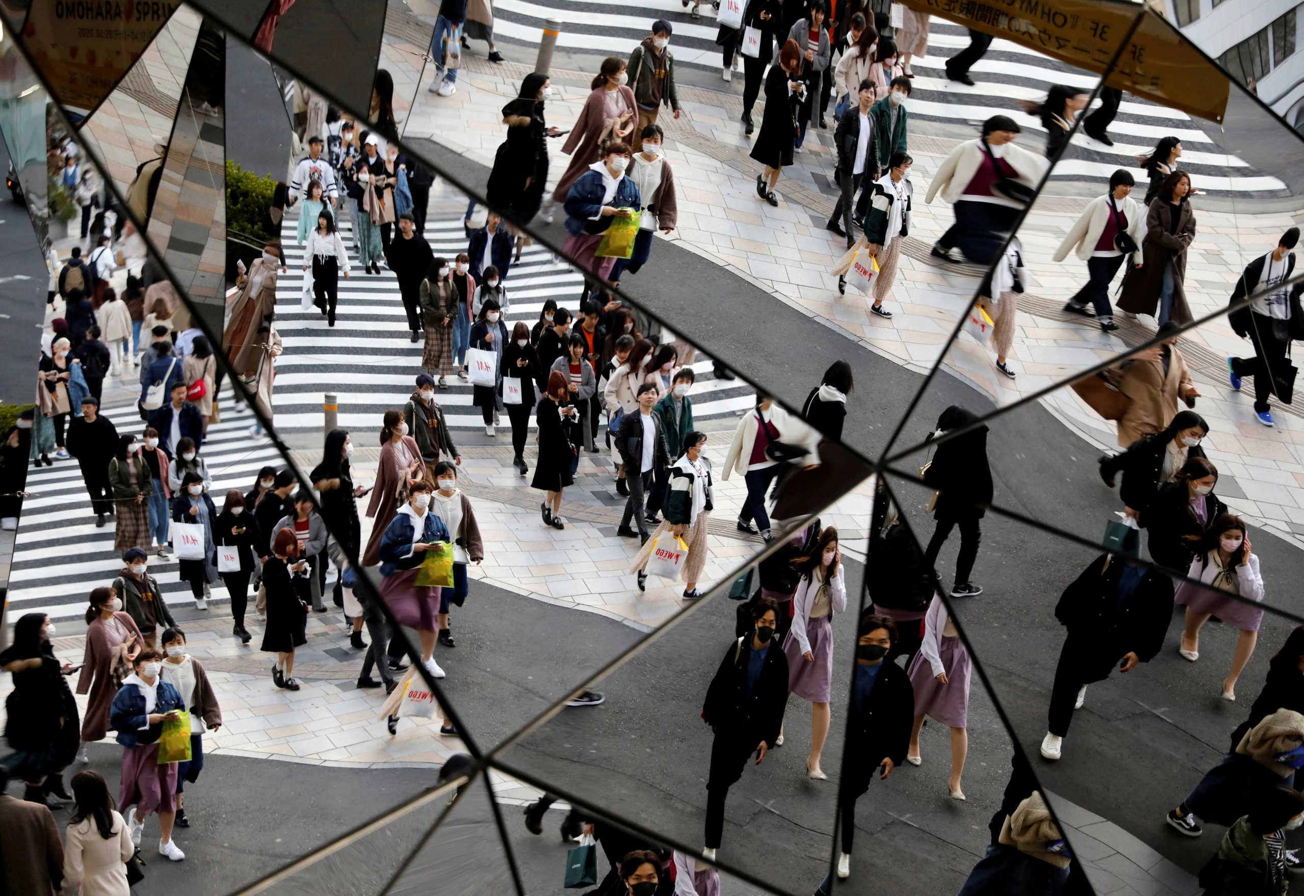 FILE PHOTO: Passersby wearing protective face masks, following an outbreak of the coronavirus disease (COVID-19), are reflected in mirrors at a shopping center in Tokyo, Japan March 26, 2020.   REUTERS
