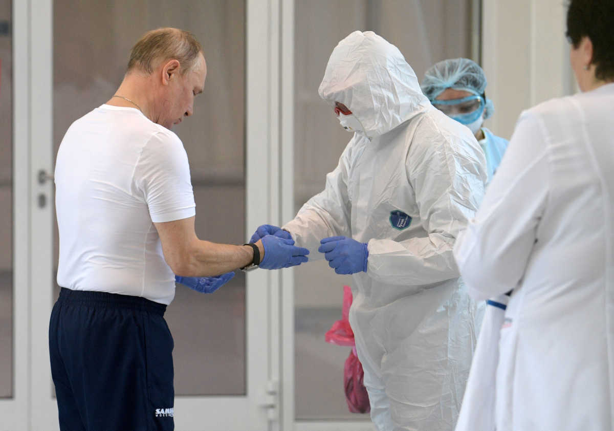 Russian President Vladimir Putin takes off protective gloves during his visit to a hospital for patients infected with coronavirus disease (COVID-19) on the outskirts of Moscow, Russia March 24, 2020. Sputnik