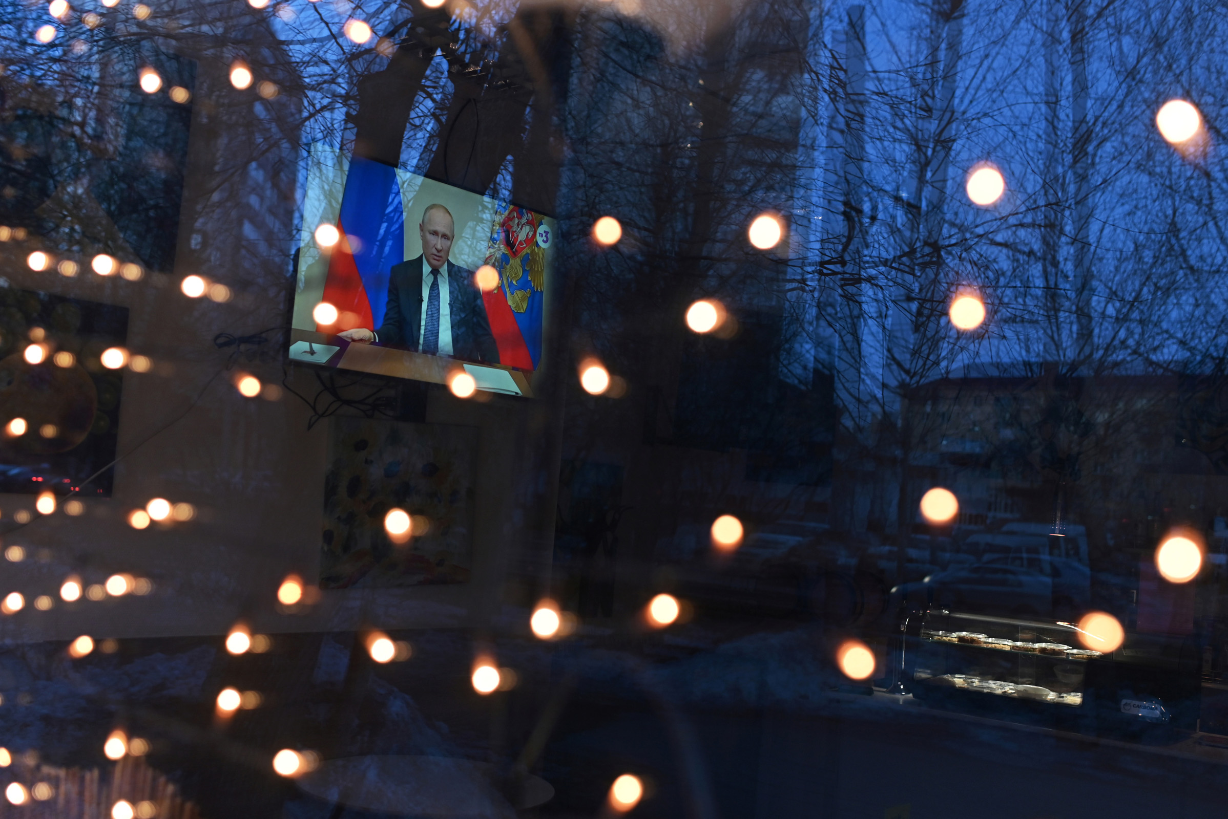 A TV set broadcasting Russian President Vladimir Putin's address to the nation on measures to combat the spread of coronavirus disease (COVID-19) is seen through the window of a cafe in Omsk, Russia March 25, 2020. REUTERS