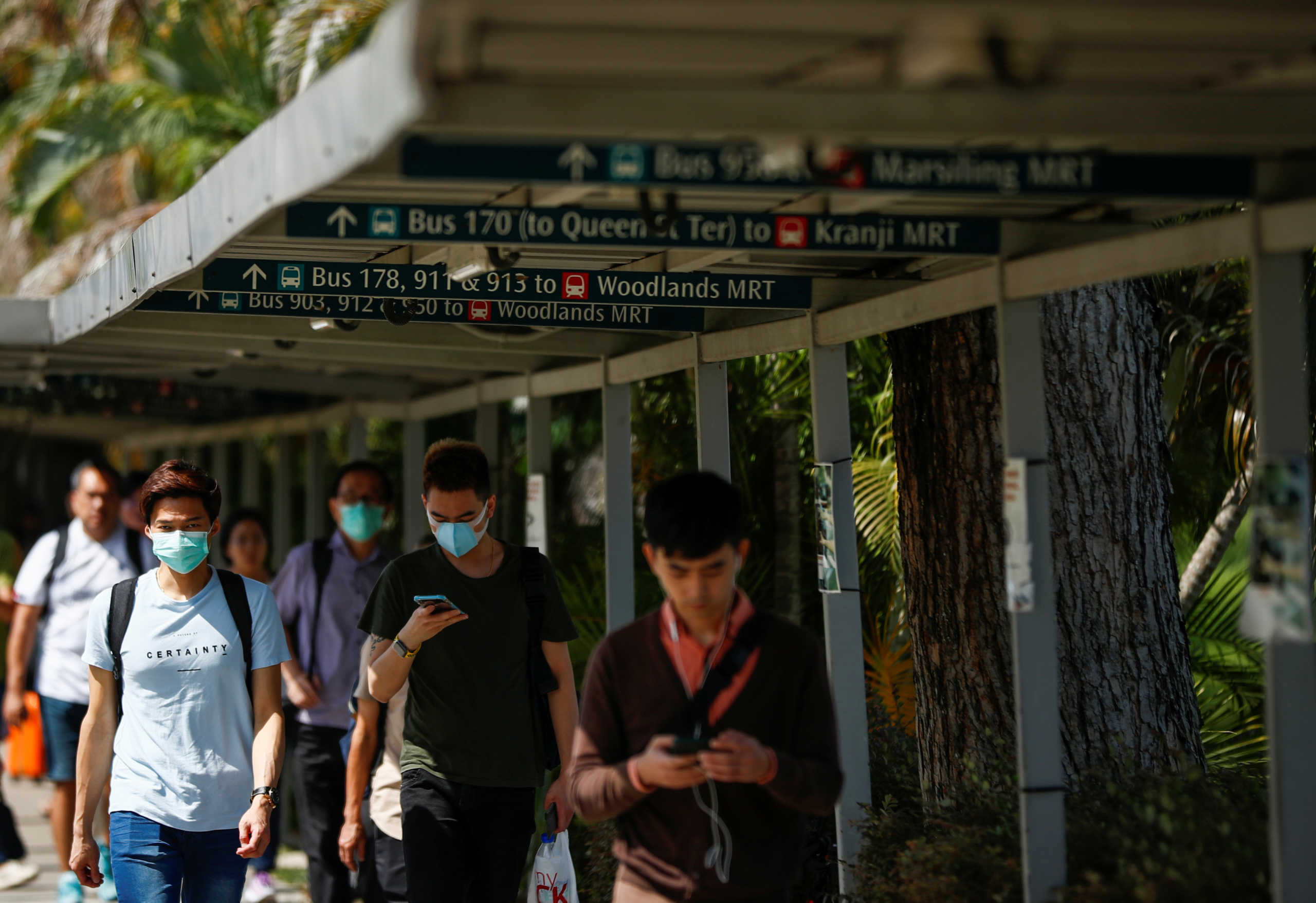 People wearing protective face masks arrive to cross the causeway from Singapore to Johor a day before Malaysia imposes a lockdown on travel due to the coronavirus outbreak in Singapore, March 17, 2020.  REUTERS