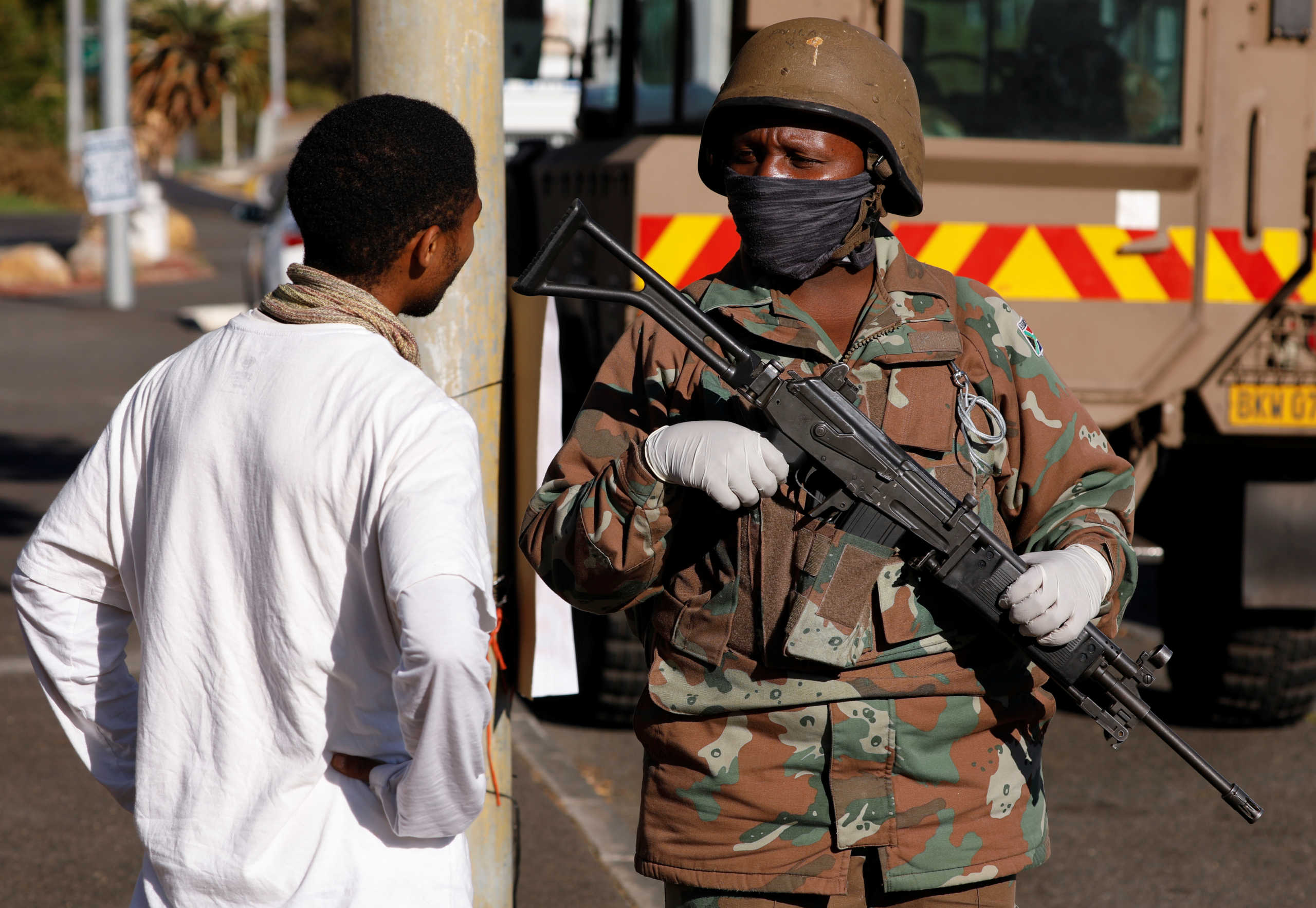 A soldier stands guard as police members check vehicles at the start of a 21 day nationwide lockdown aimed at limiting the spread of coronavirus disease (COVID-19), in Cape Town, South Africa, March 27, 2020. Reuters