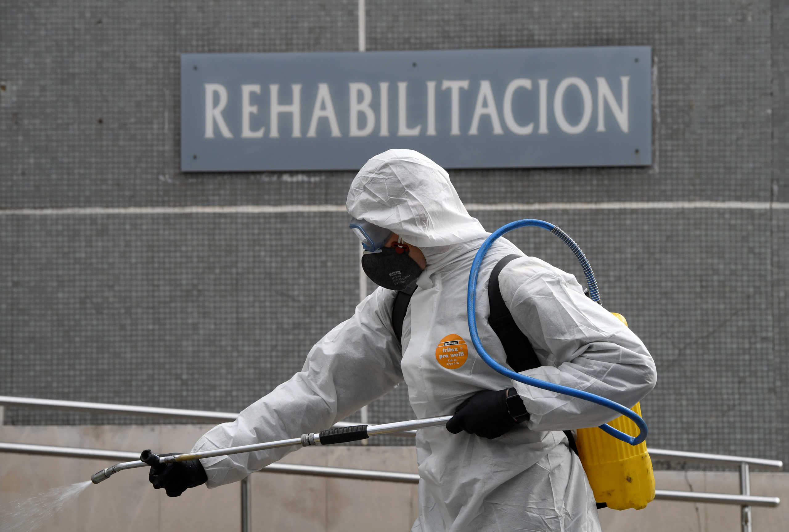 A member of the Military Emergency Unit (UME) sprays disinfectant to prevent the spread of the coronavirus disease (COVID-19) at Cabuenes Hospital in front of a sign reading Rehabilitation during a 15-day state of emergency declared to combat the outbreak of the coronavirus disease (COVID-19) in Gijon, Spain, March 18, 2020.REUTERS